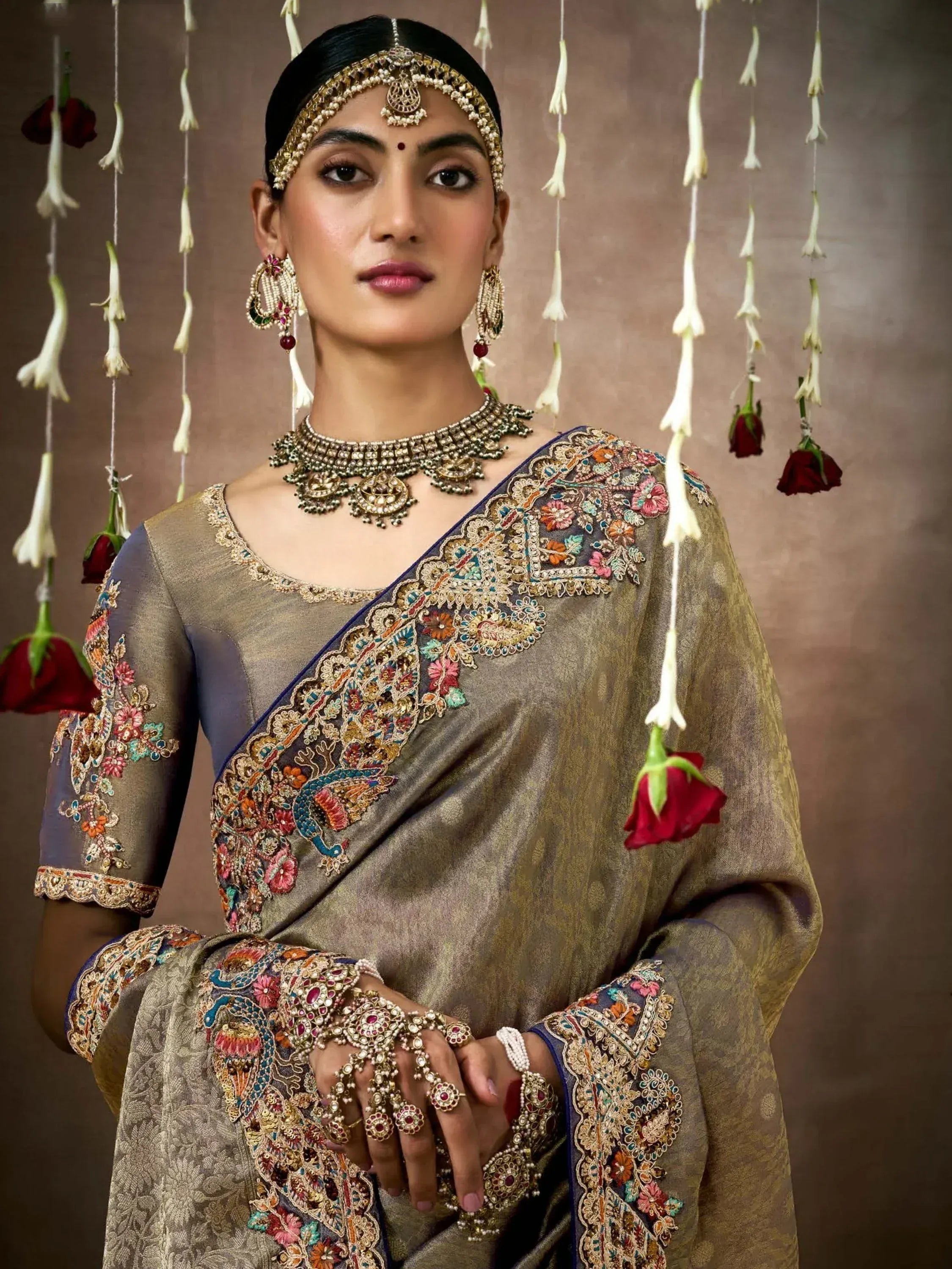 Elegant Indian saree with intricate floral embroidery, traditional jewelry, and festive floral backdrop