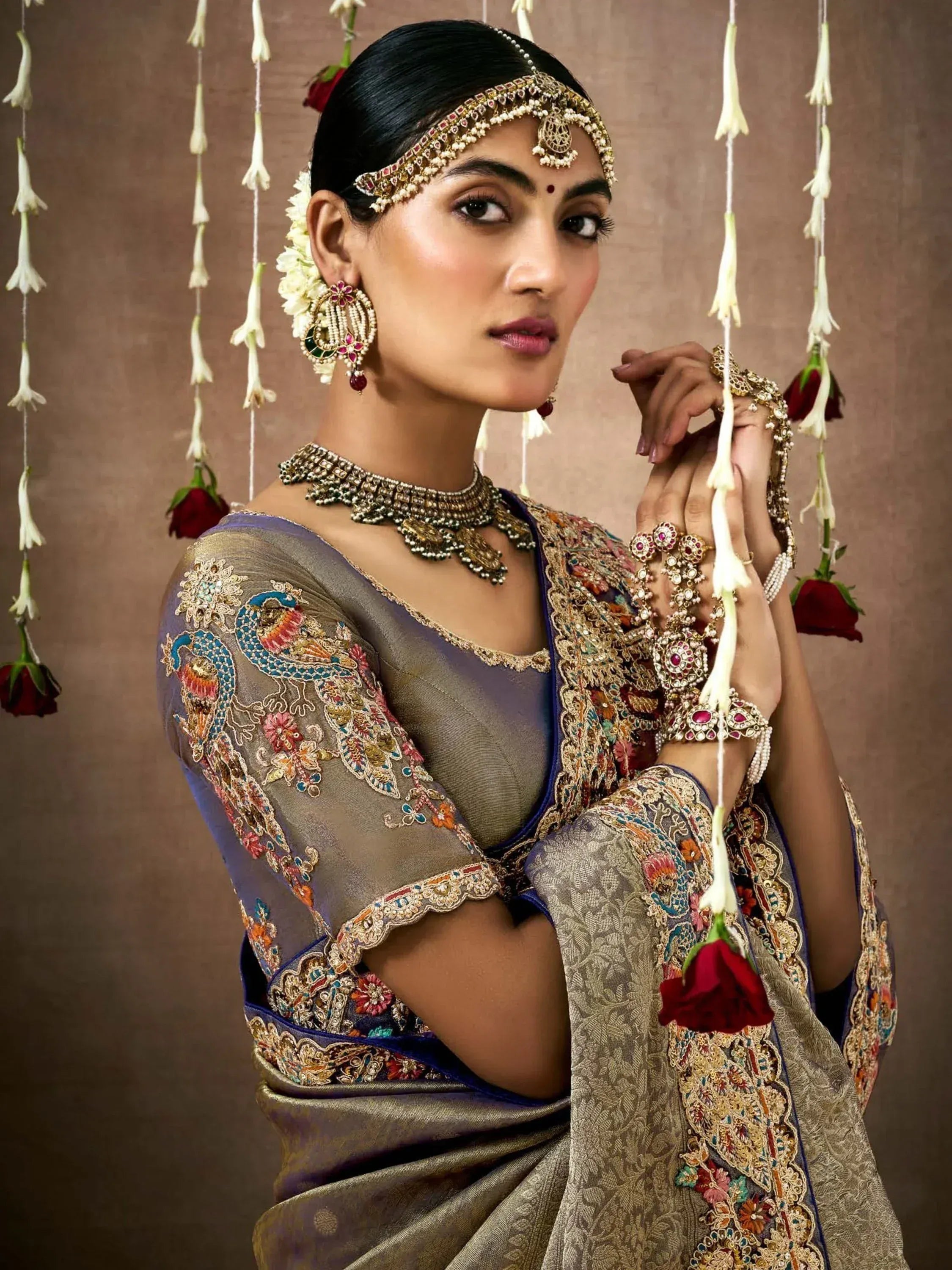 Elegant Indian bride in embroidered saree with peacock motifs, traditional jewelry, and floral decor
