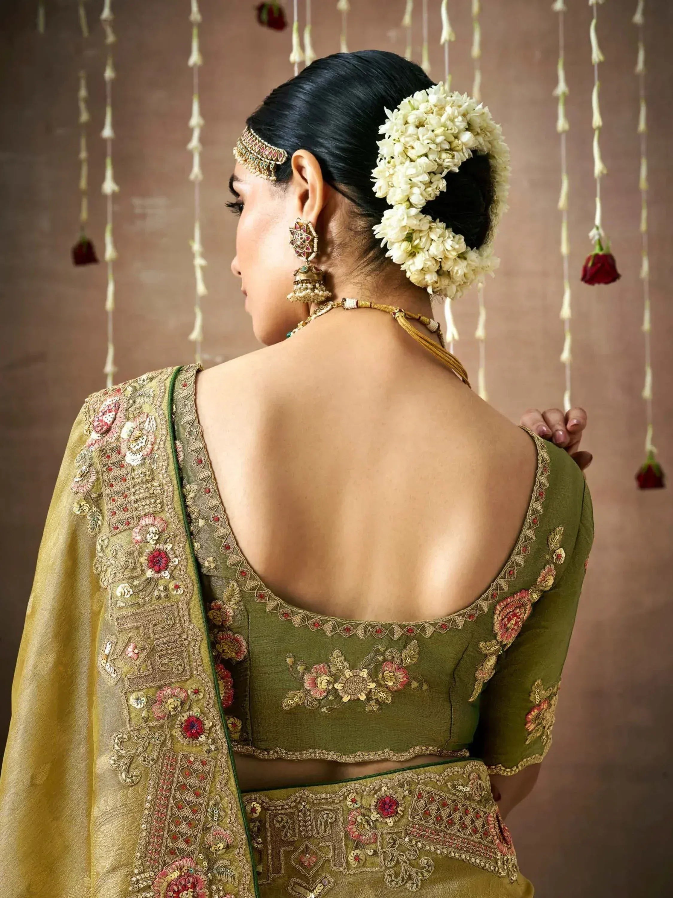 Elegant olive green lehenga choli with floral embroidery, backless blouse, and traditional jewelry for Indian weddings