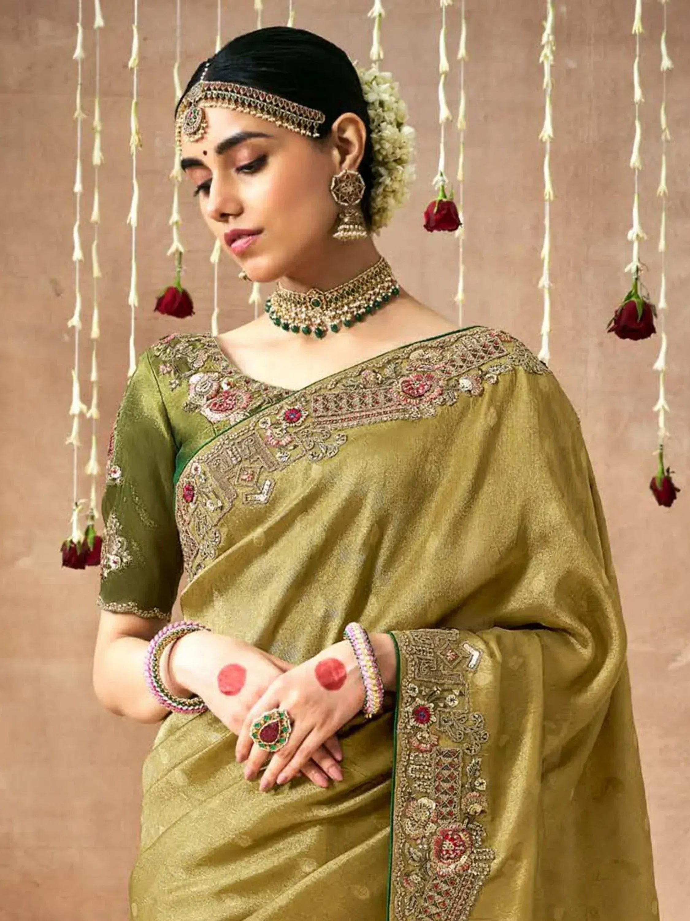 Olive green embroidered saree with heavy blouse, traditional jewelry, and floral hair accessory for Indian ethnic wear