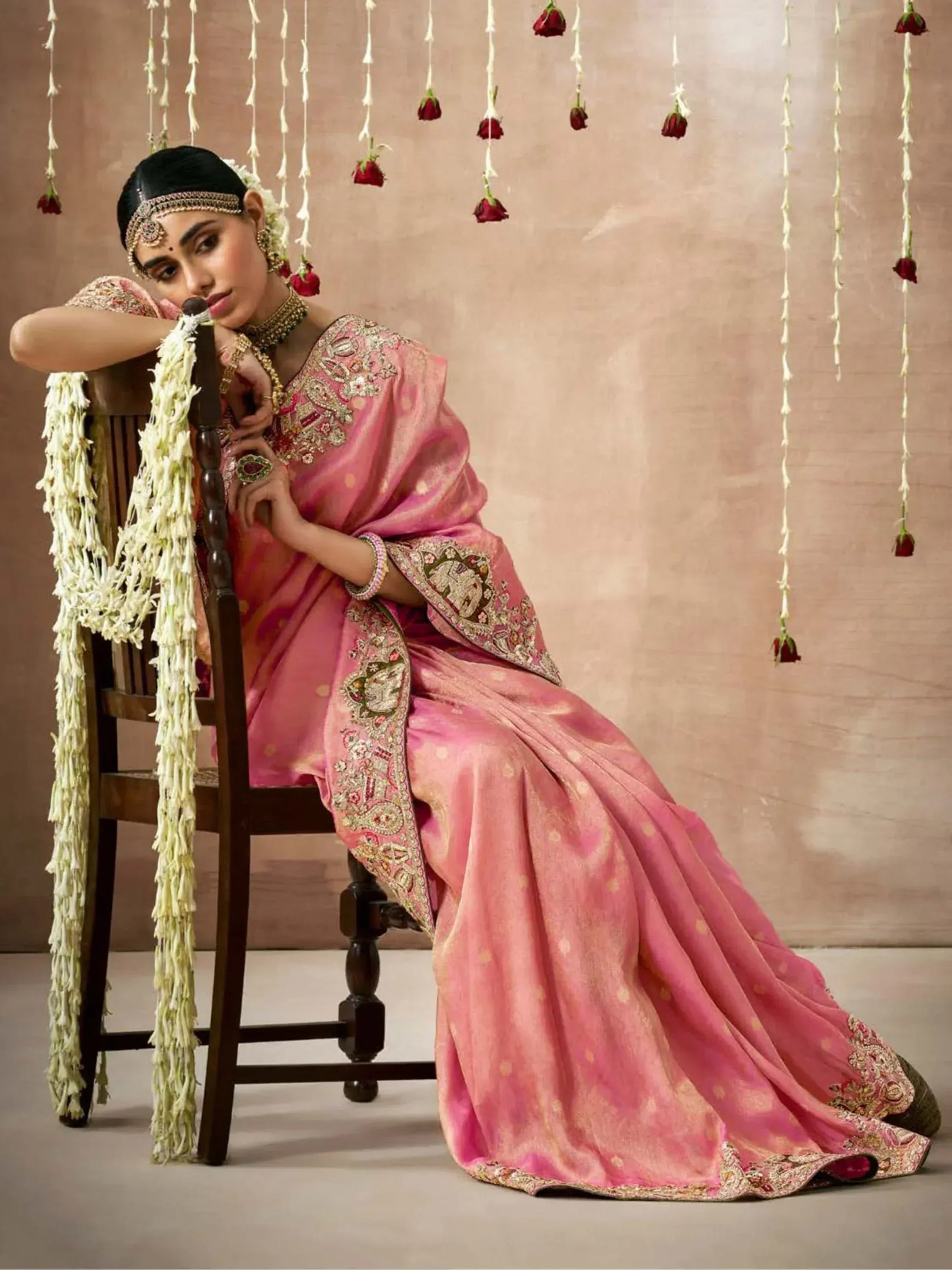 Woman in pink embroidered saree with floral decor, traditional Indian ethnic wear