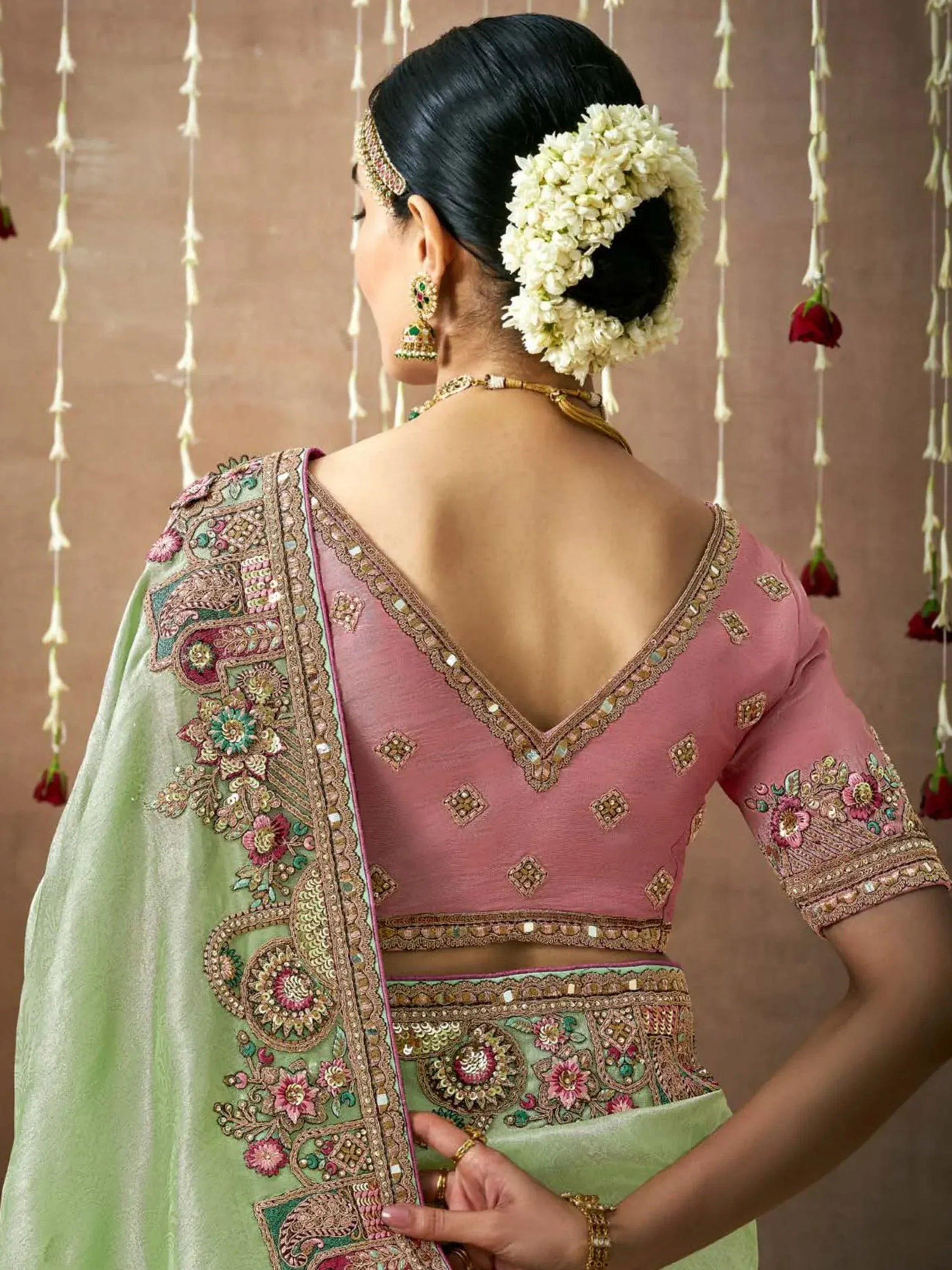 Pink and mint green embroidered lehenga choli with floral jewelry, perfect for Indian weddings and festive occasions.