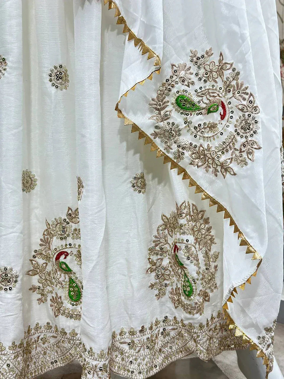 White ethnic lehenga with peacock embroidery and gold trim, perfect for Indian weddings and festive occasions.