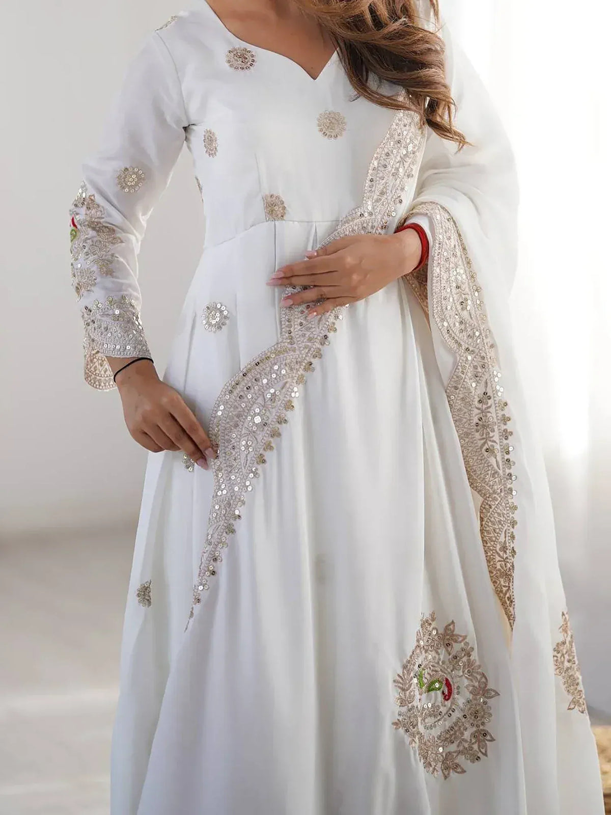 White ethnic Anarkali with gold sequin embroidery and floral motifs, perfect for festive occasions