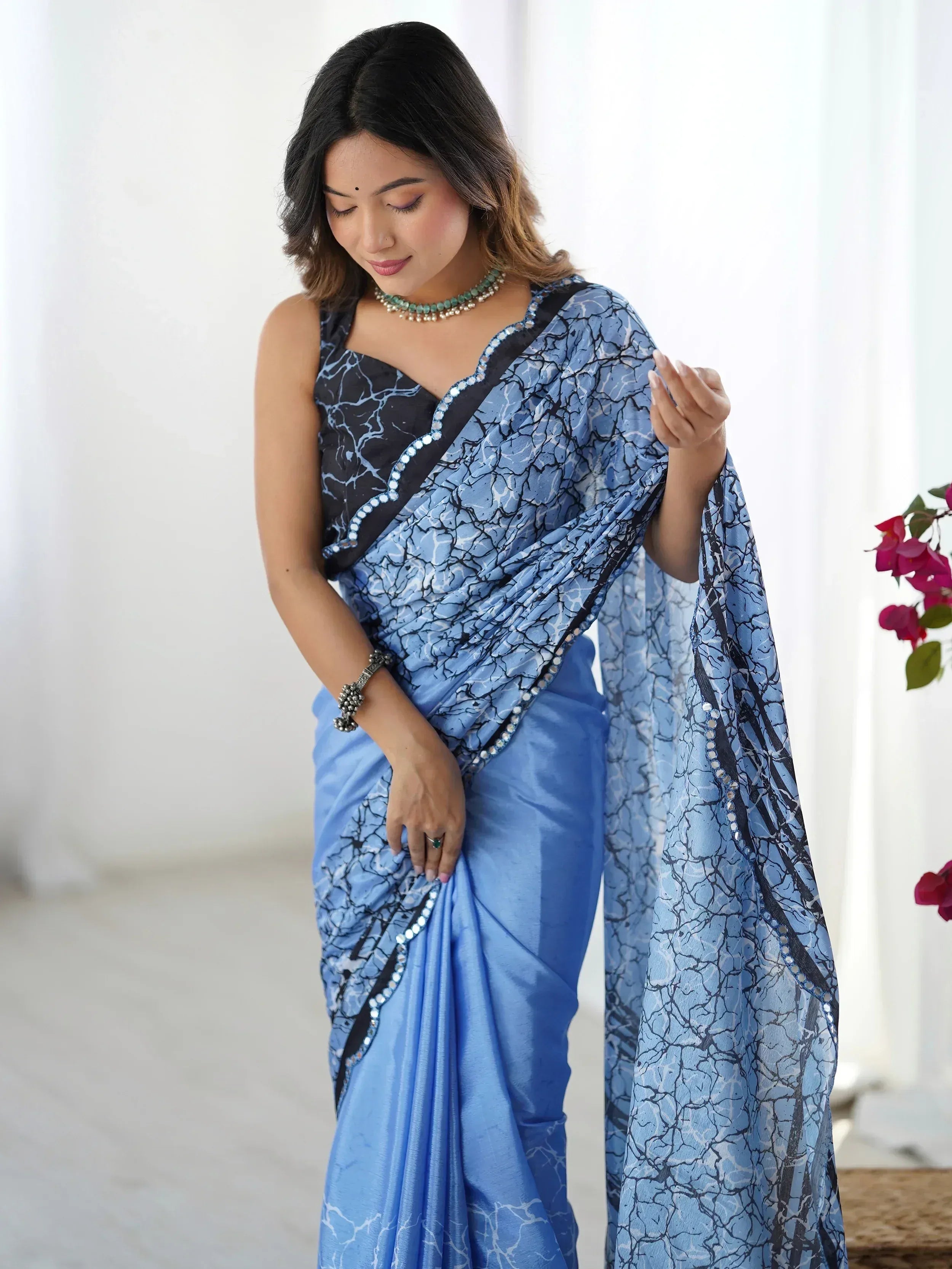 Blue printed saree with black border and mirror work, styled with ethnic jewelry for Indian occasions