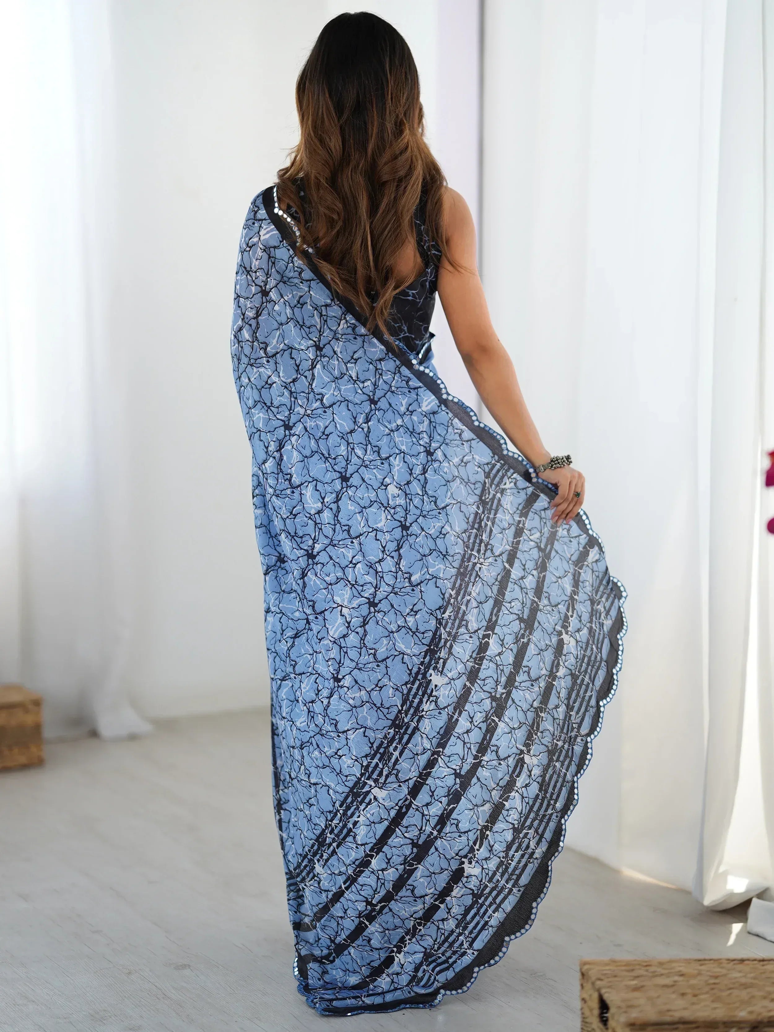 Blue printed saree with black border and sequin detailing, styled with sleeveless blouse for ethnic wear