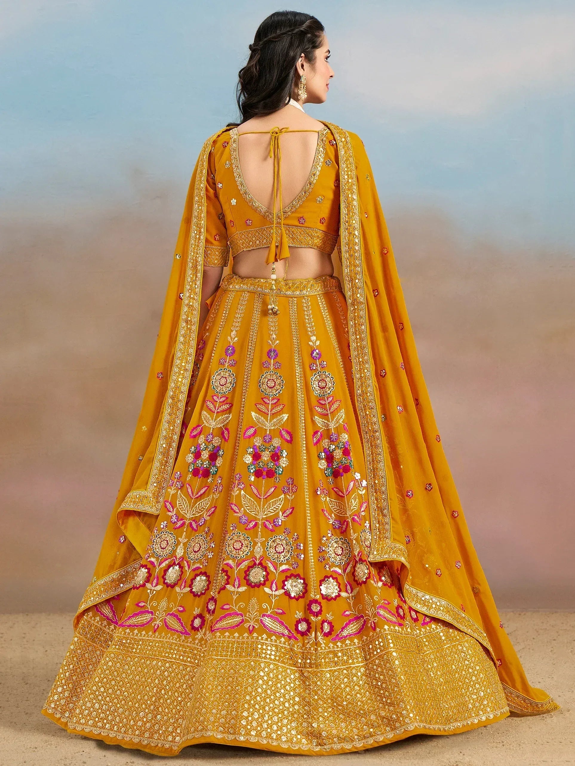 Yellow embroidered lehenga choli with floral motifs and open back design, perfect for Indian weddings and festive occasions.
