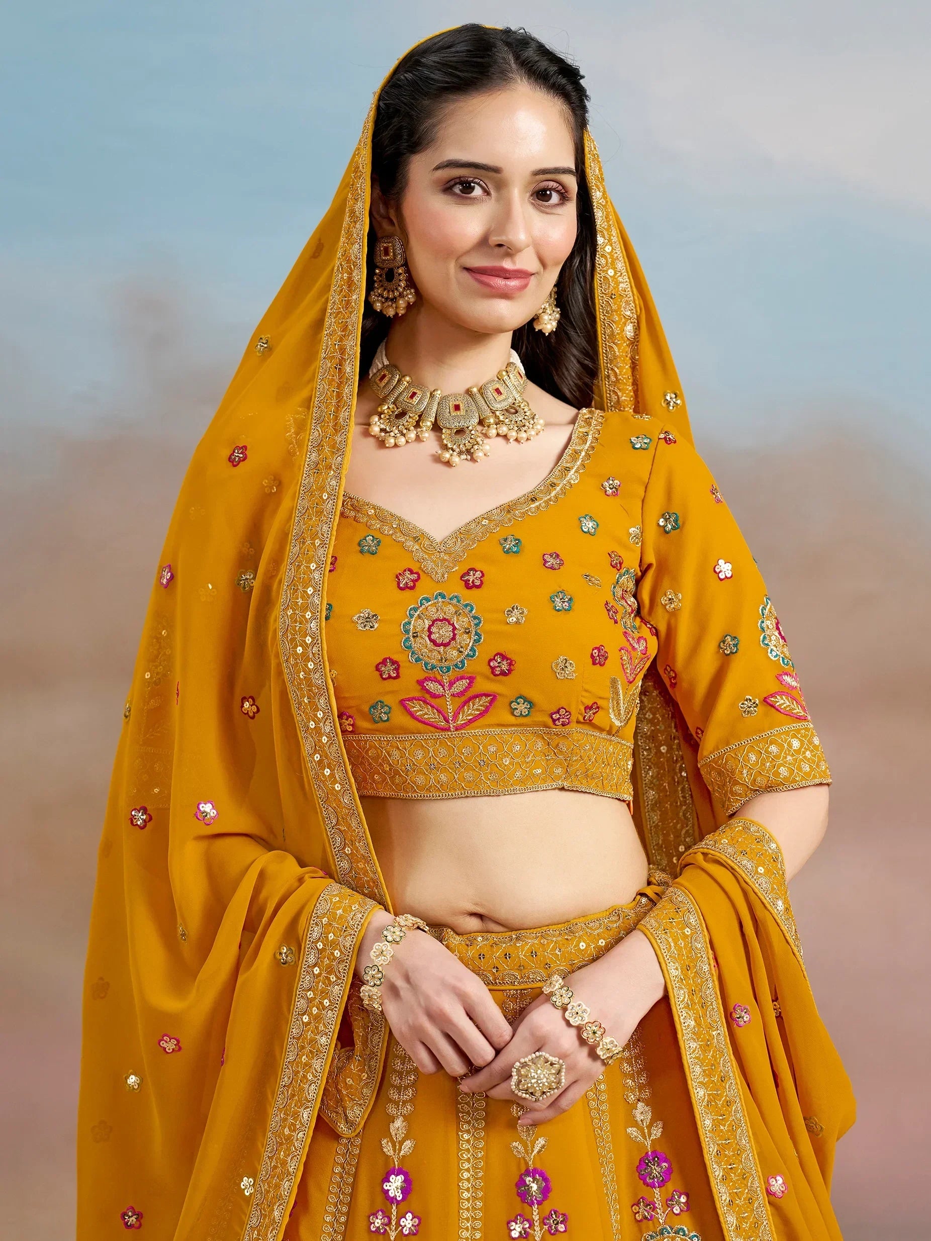 Yellow embroidered lehenga choli with floral motifs and gold jewelry, ideal for Indian ethnic occasions