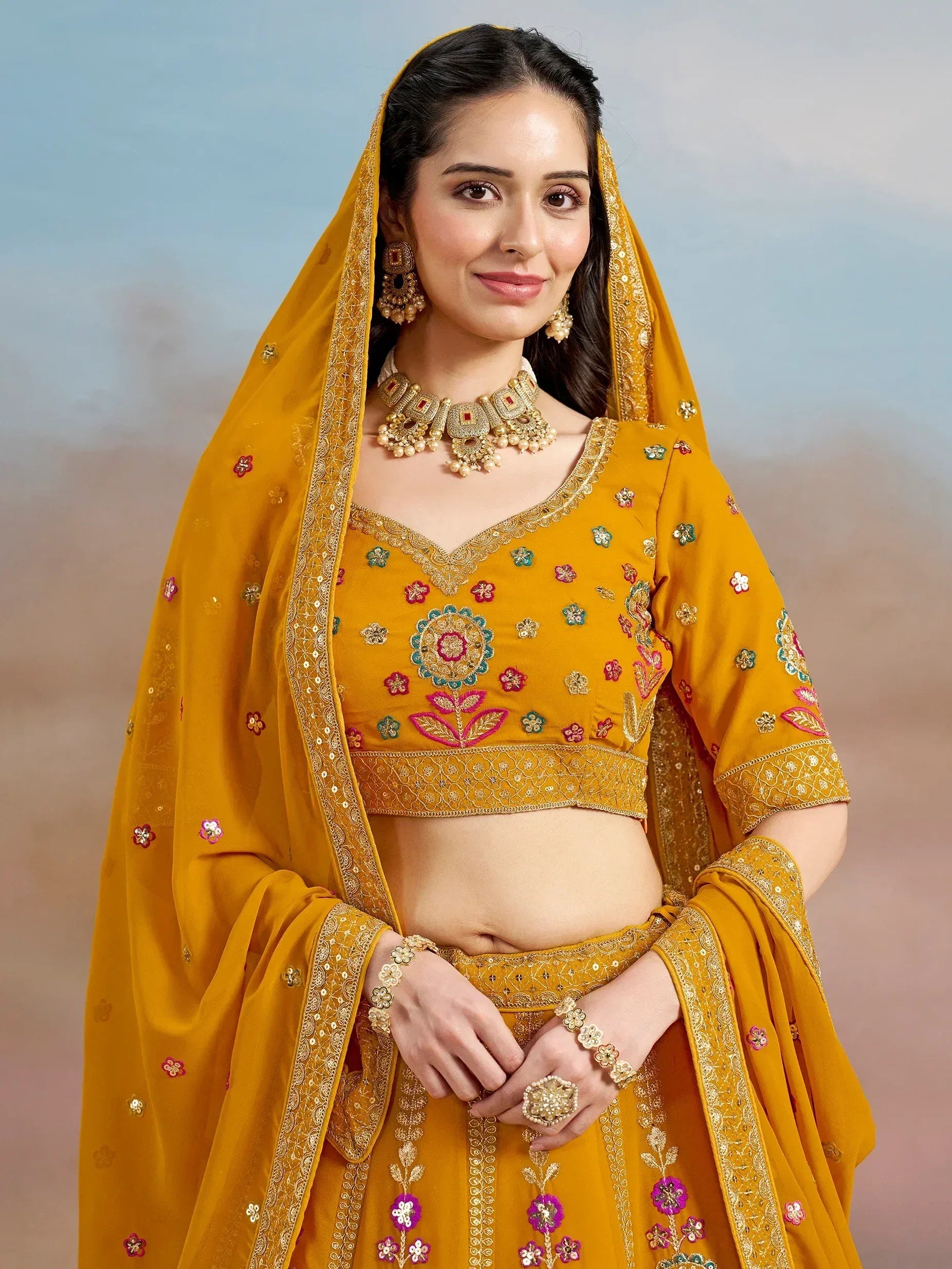 Yellow embroidered lehenga choli with floral motifs and gold jewelry, ideal for Indian ethnic occasions