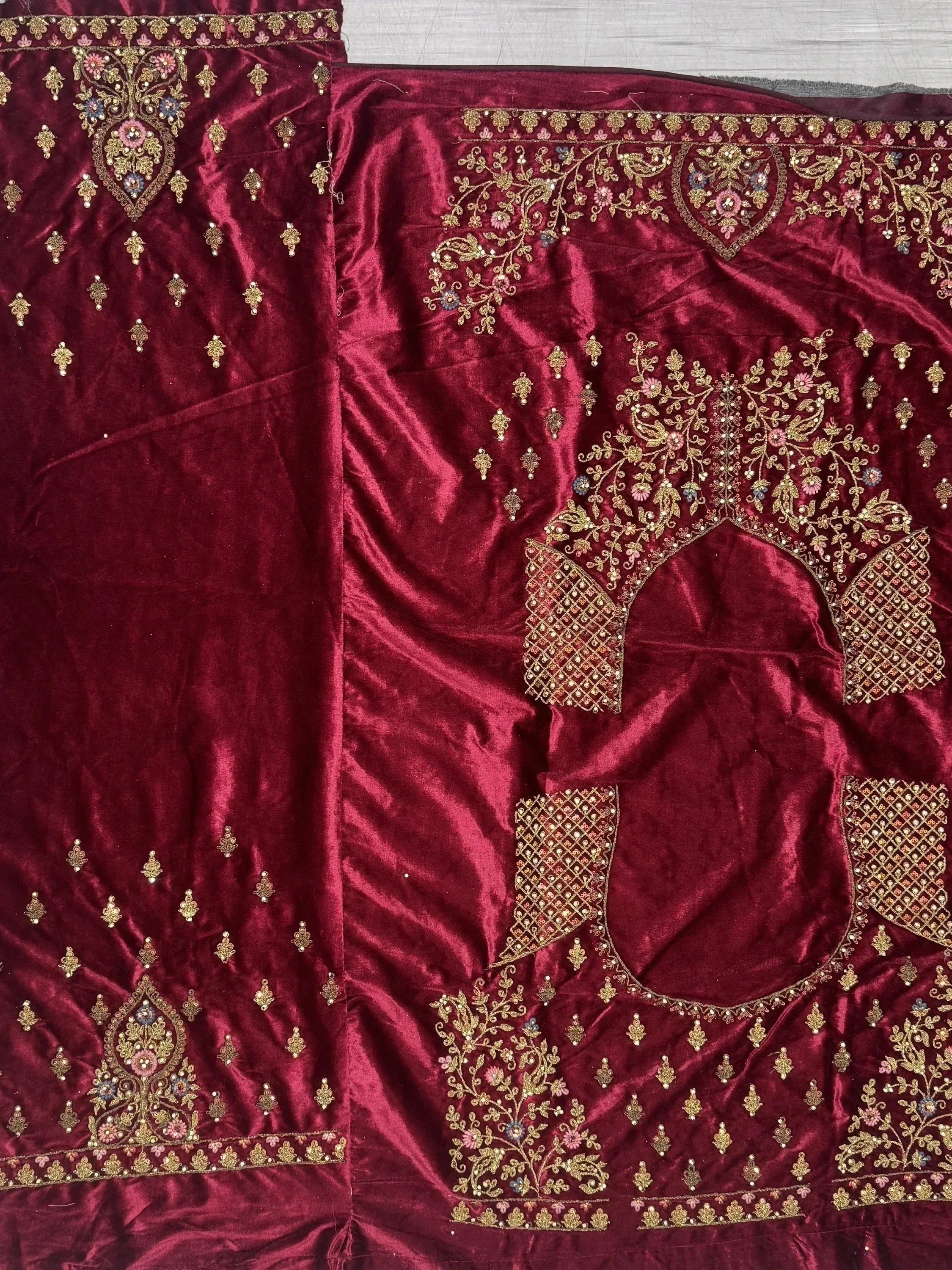 Rich maroon velvet lehenga choli with intricate gold floral embroidery and embellished borders, perfect for Indian ethnic wear.