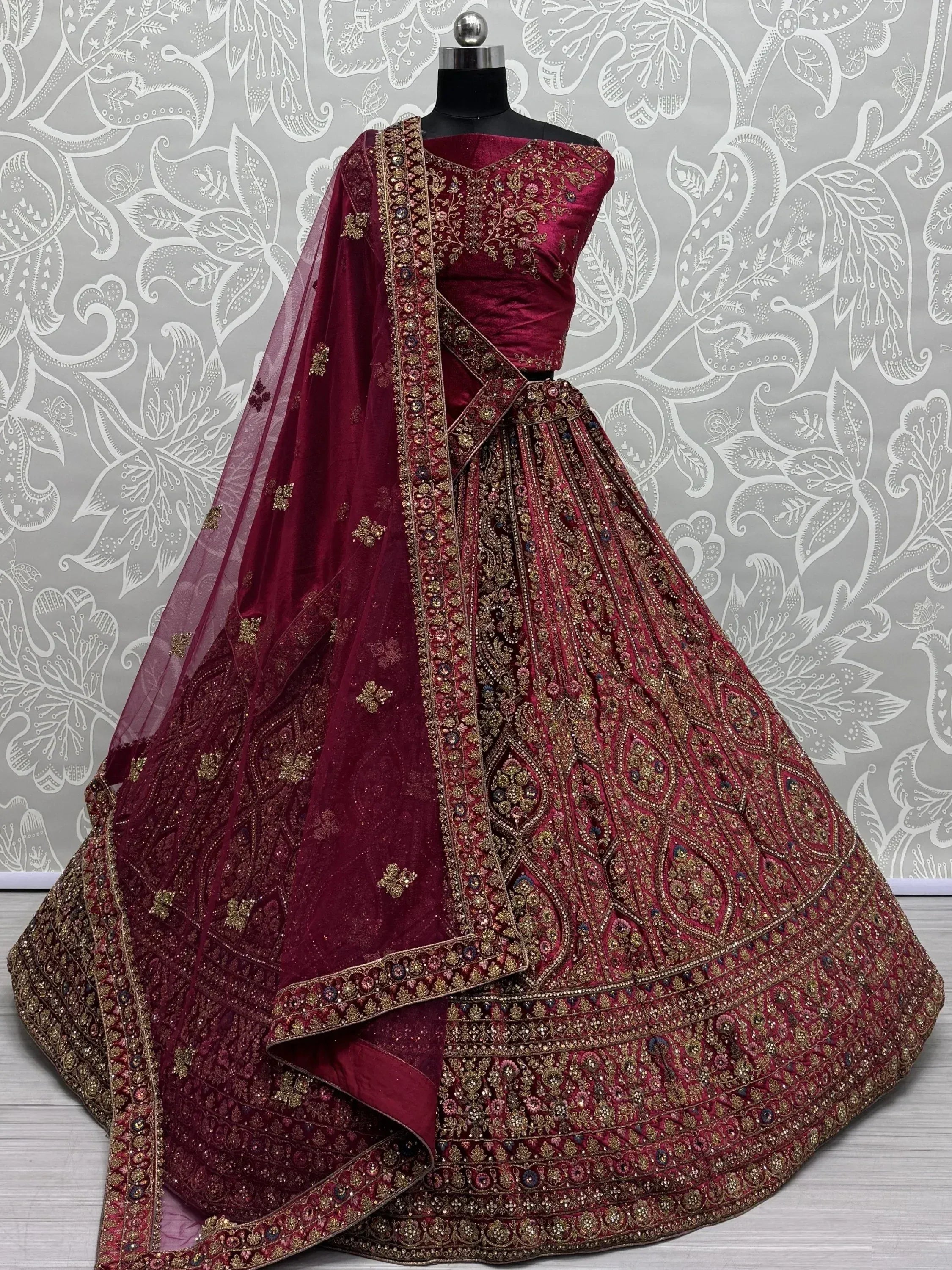 Burgundy velvet designer lehenga choli with heavy gold embroidery and matching dupatta, perfect for weddings.