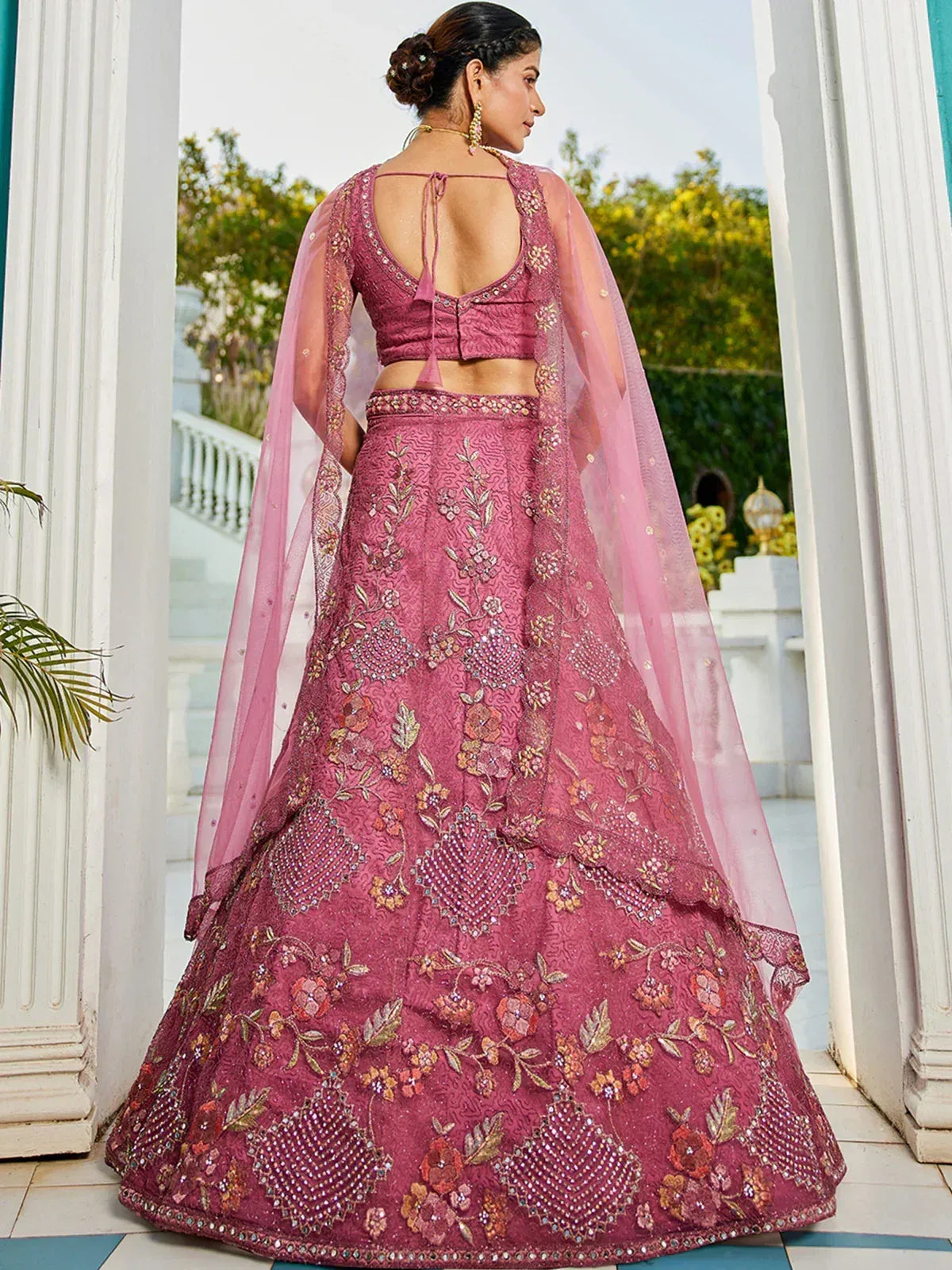 Pink embroidered lehenga choli with floral motifs and sheer dupatta, perfect for Indian weddings or festive occasions.