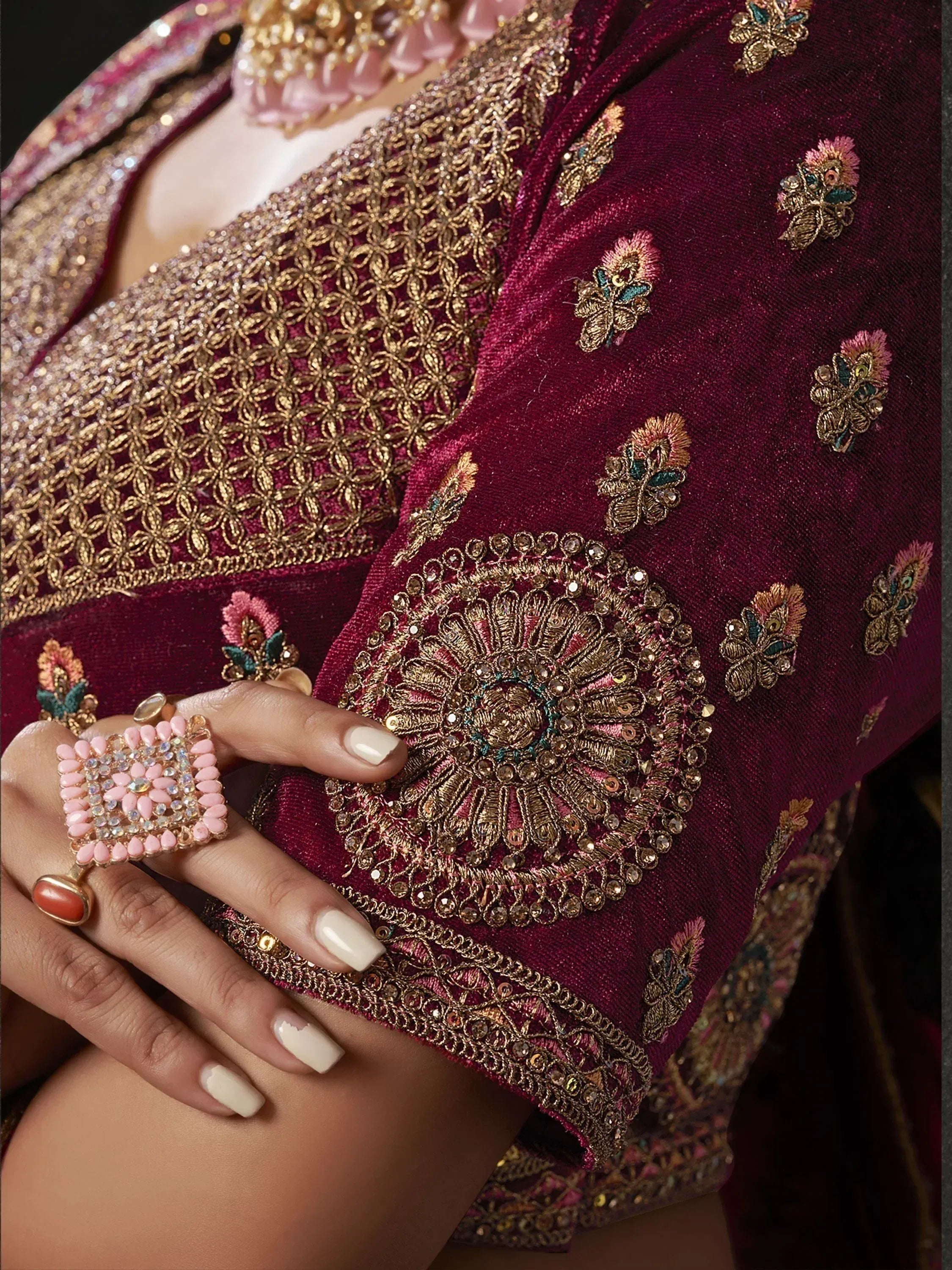Maroon velvet lehenga choli with gold embroidery and floral motifs, paired with statement rings