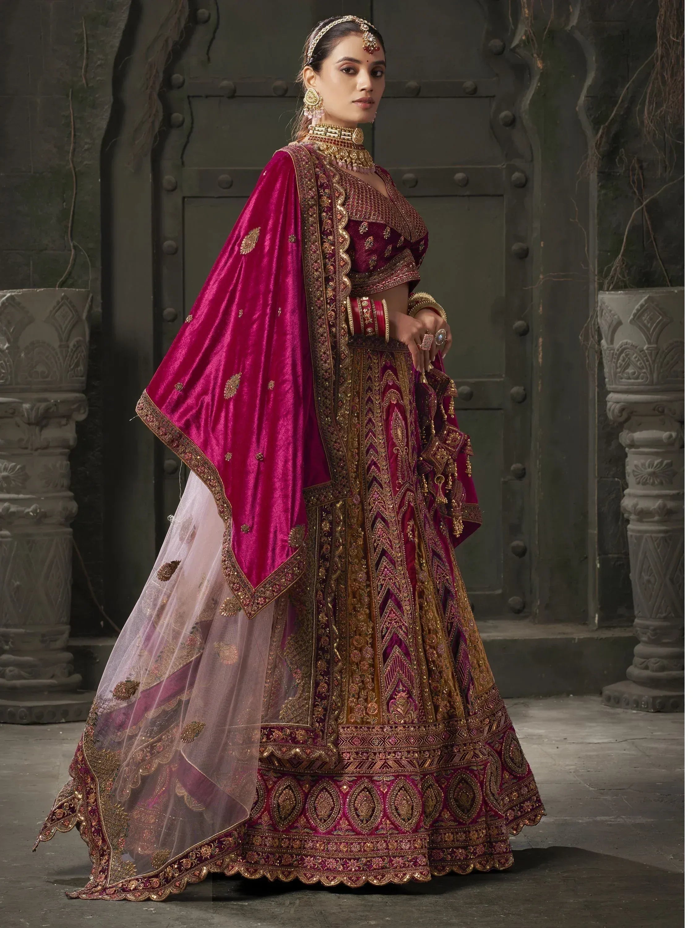 Luxury maroon velvet lehenga choli with gold embroidery, perfect for Indian weddings and festive occasions.