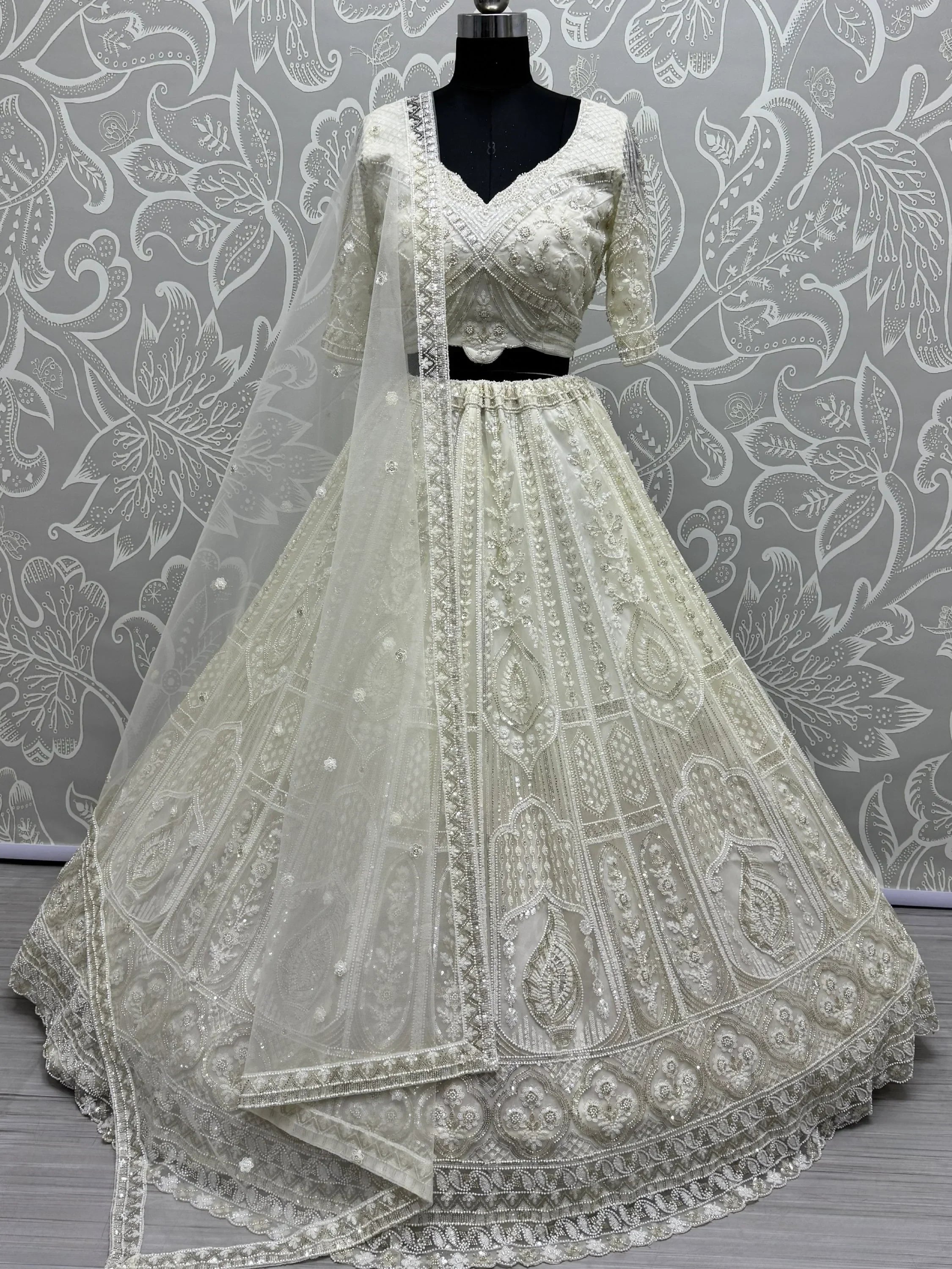 Elegant ivory designer lehenga choli with heavy embroidery and net dupatta, perfect for weddings and festive occasions.