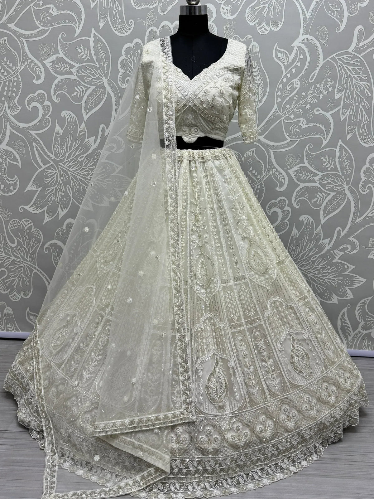 Elegant ivory designer lehenga choli with heavy embroidery and net dupatta, perfect for weddings and festive occasions.