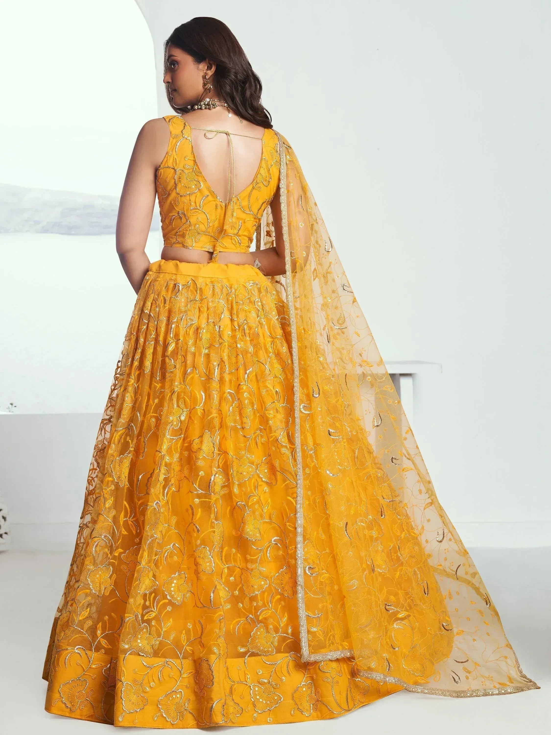 Yellow embroidered lehenga choli with floral design and sheer dupatta, perfect for Indian ethnic occasions.