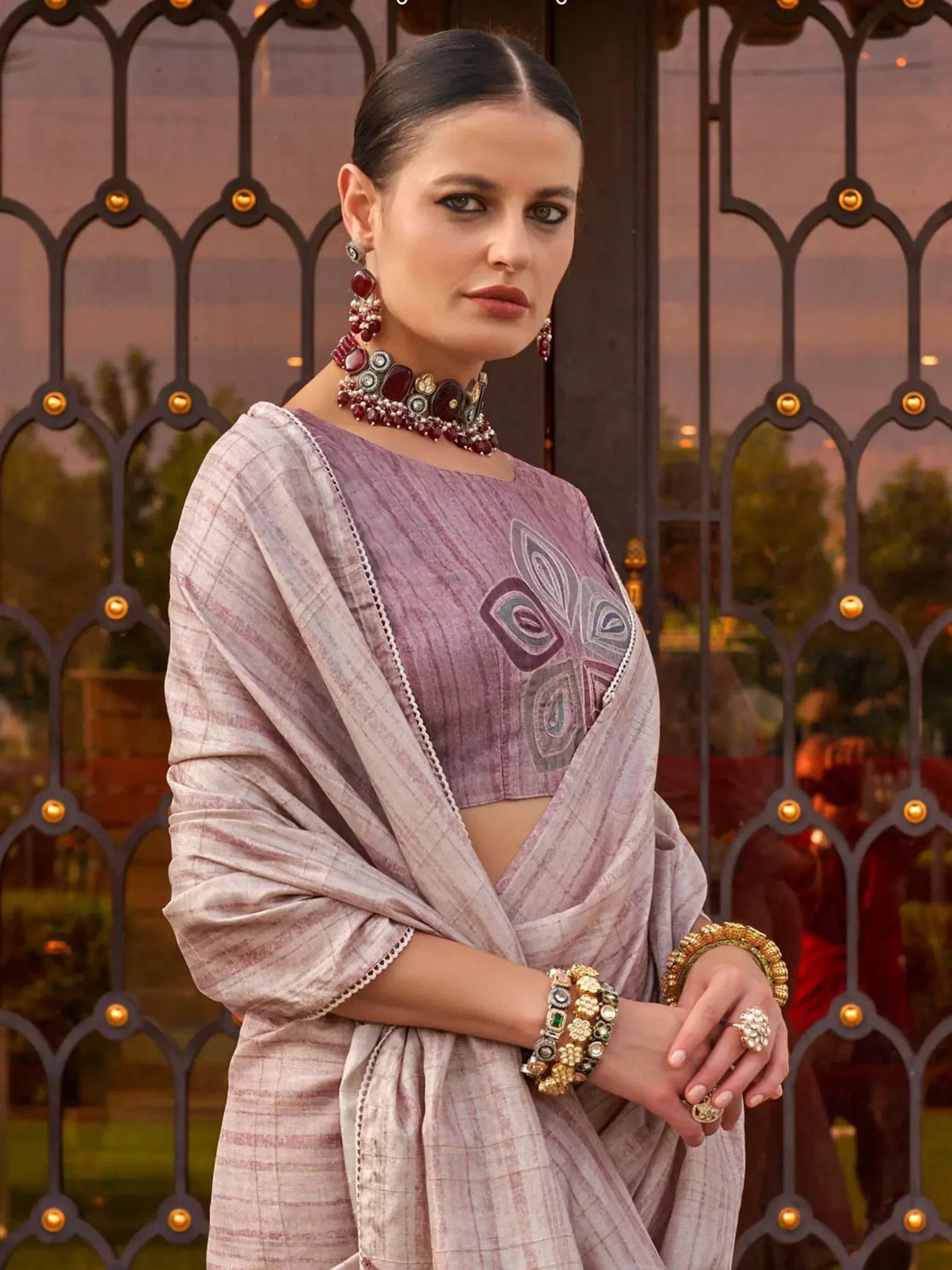 Woman in purple embroidered crop top and matching saree with statement jewelry, ethnic Indian wear