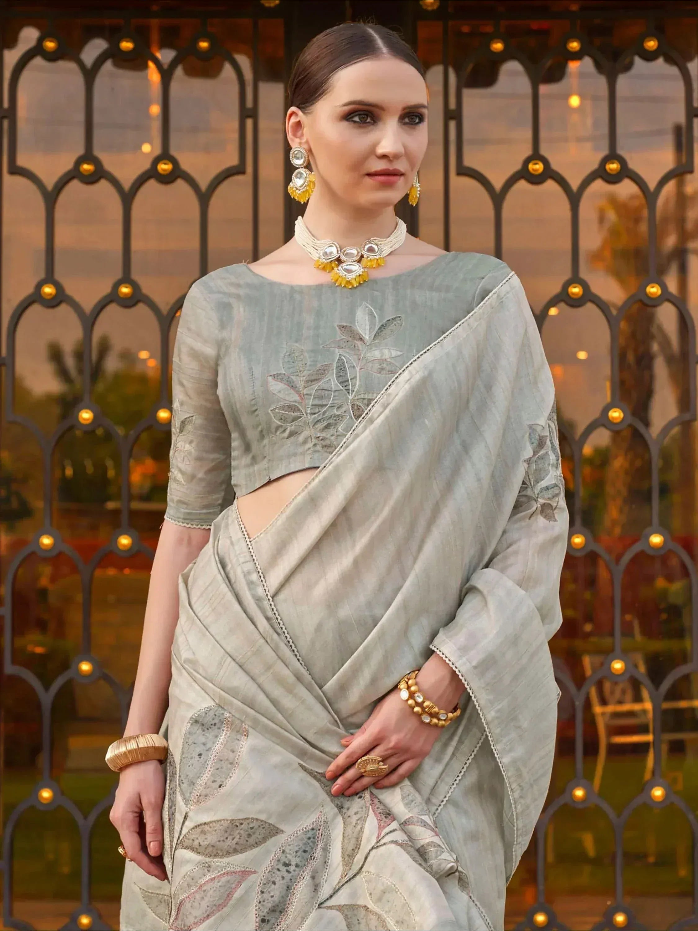 Elegant grey saree with leaf embroidery, designer blouse, and traditional jewelry for Indian ethnic wear.