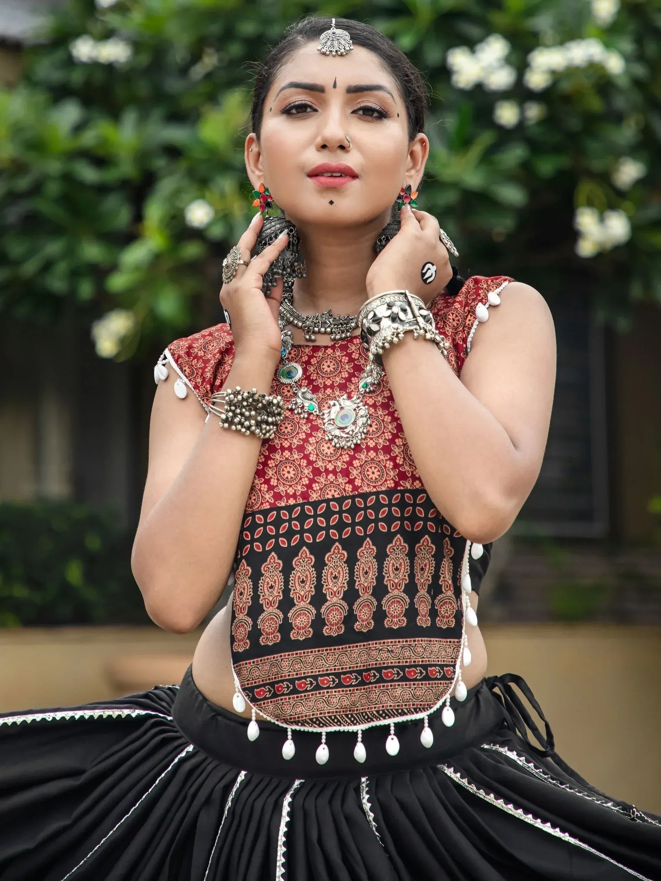 Woman in traditional Indian ethnic wear with red and black printed top, black skirt, and silver jewelry