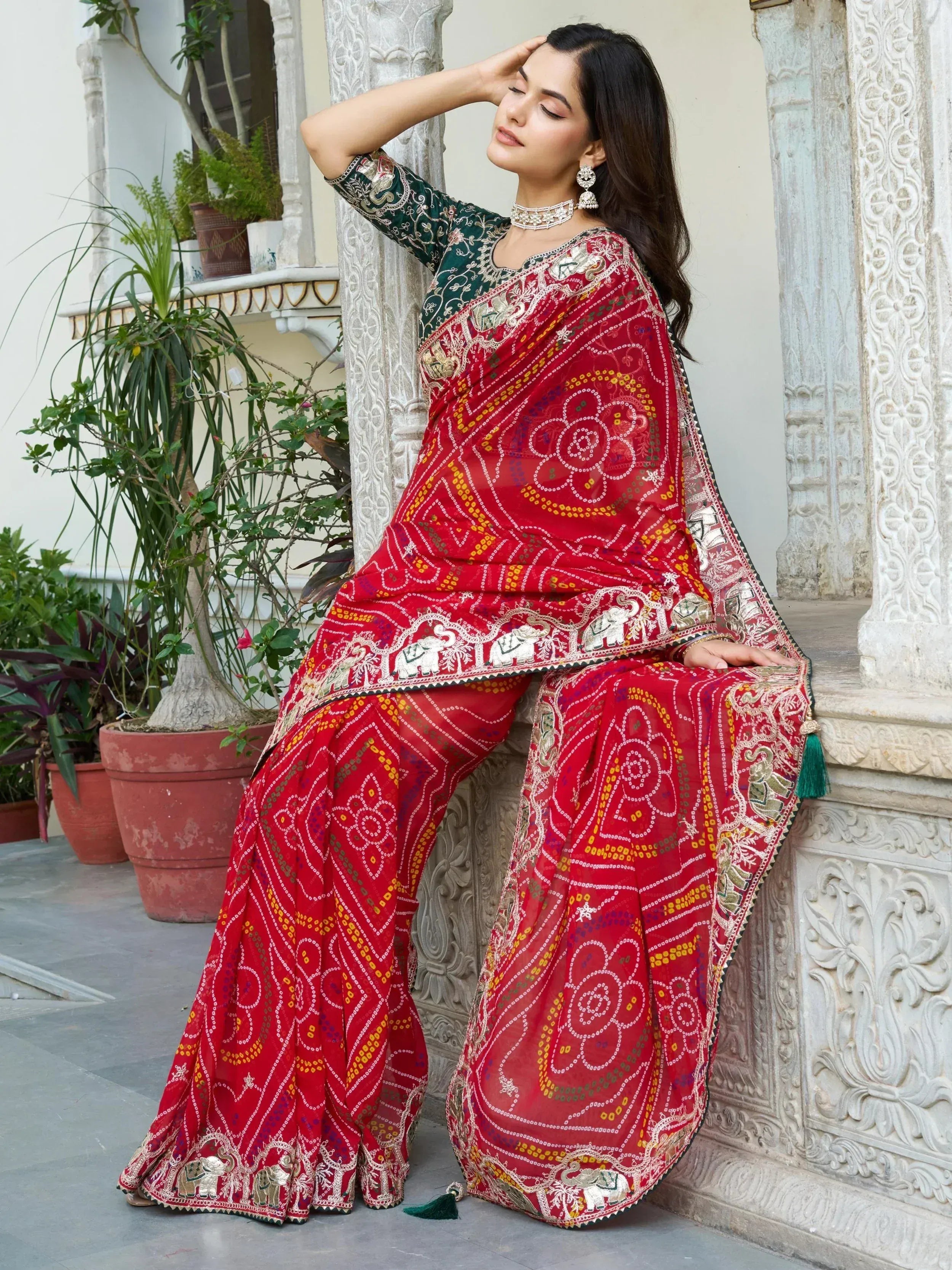 Red embroidered saree with elephant motifs, paired with green blouse, styled for Indian ethnic wear