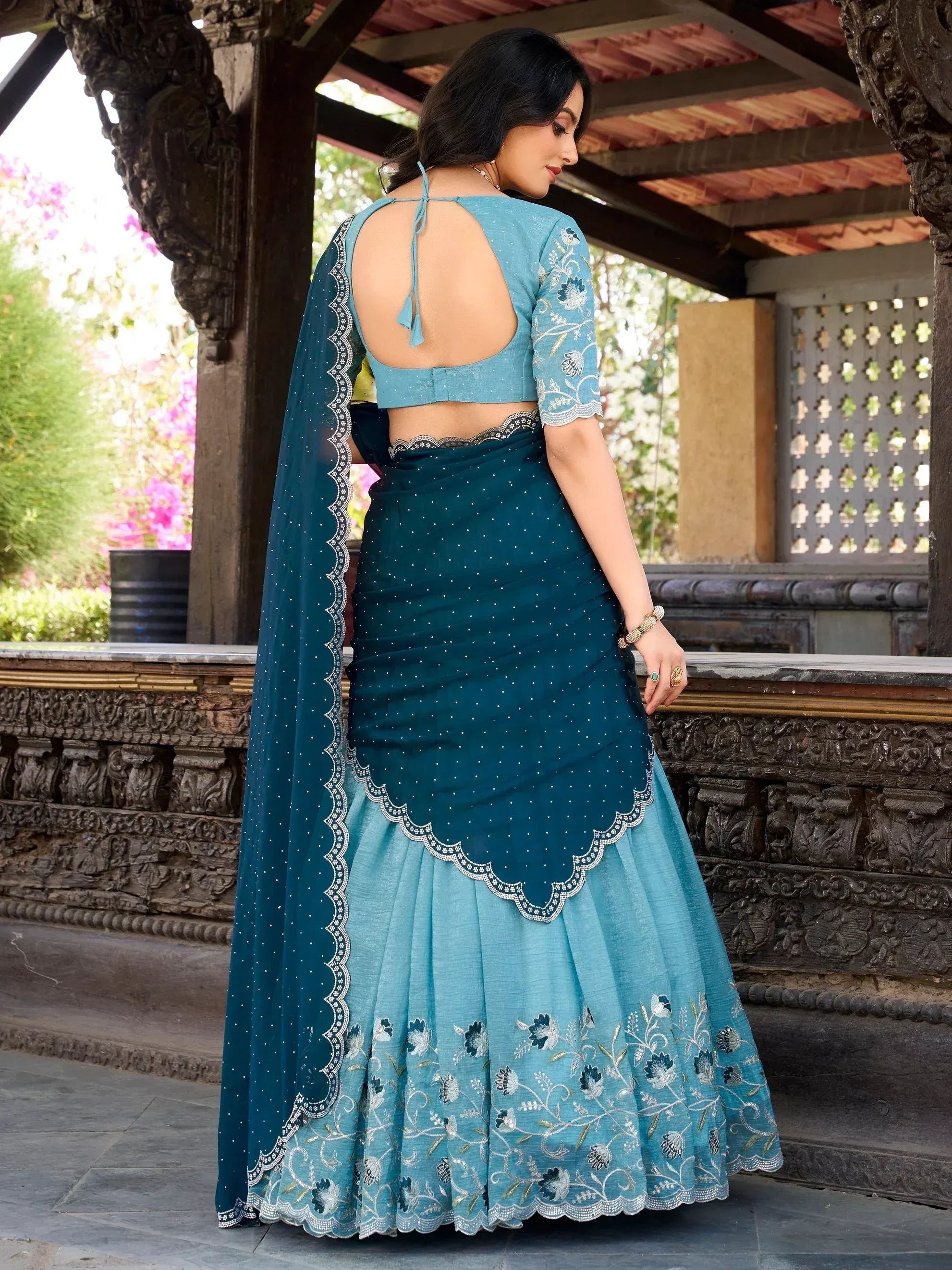 Teal and blue embroidered lehenga choli with backless blouse and floral dupatta, perfect for Indian ethnic occasions.