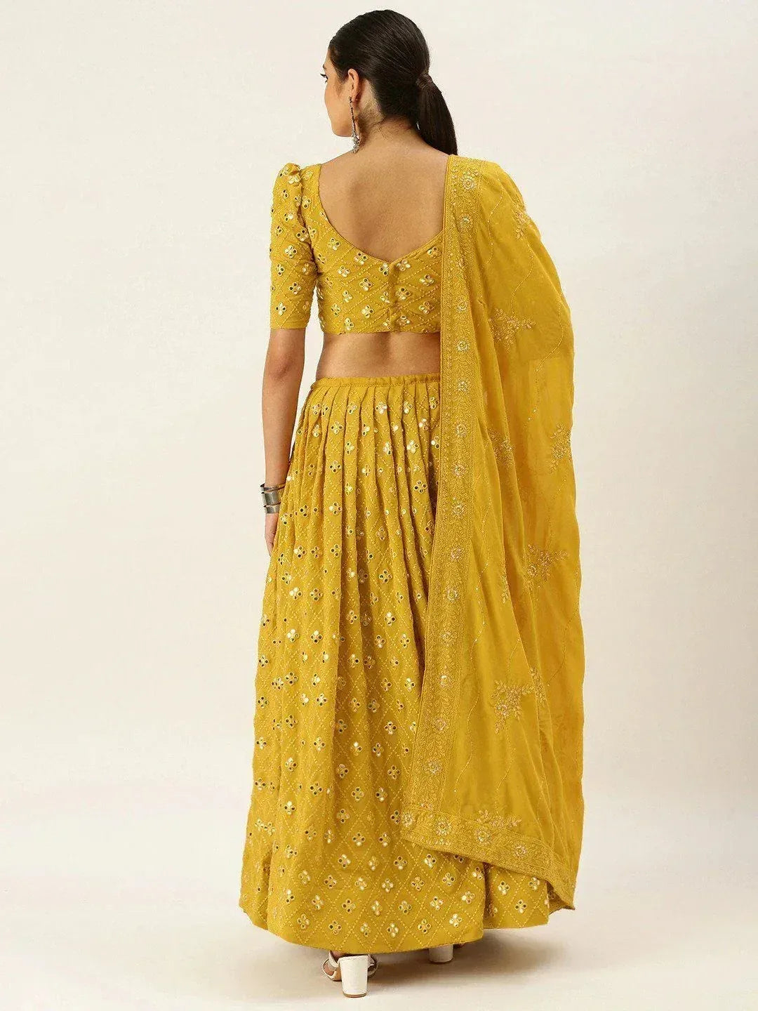 Yellow embroidered lehenga choli with mirror work and sheer dupatta, back view