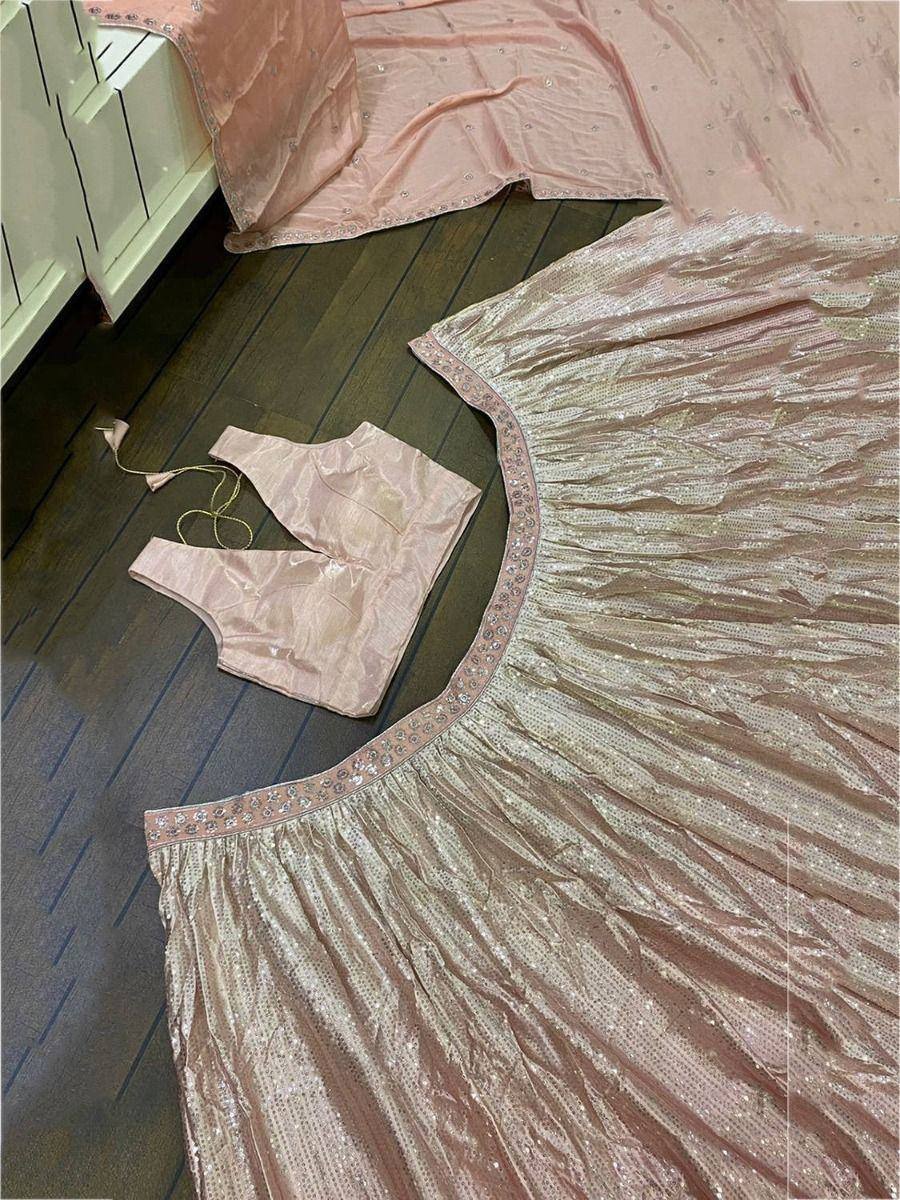 Pink sequin lehenga choli set with embroidered border, laid on wooden floor