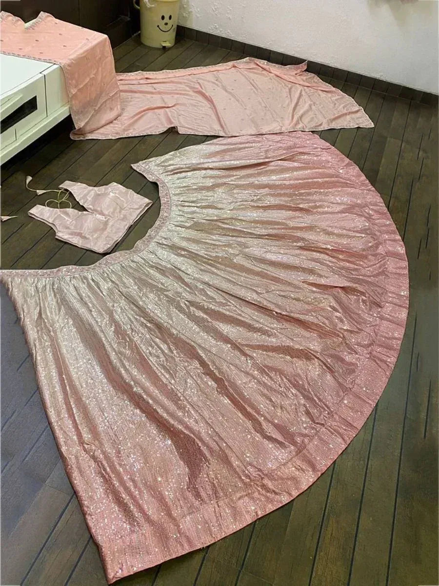 Pink shimmer lehenga choli set with sequin skirt and blouse, laid out on wooden floor