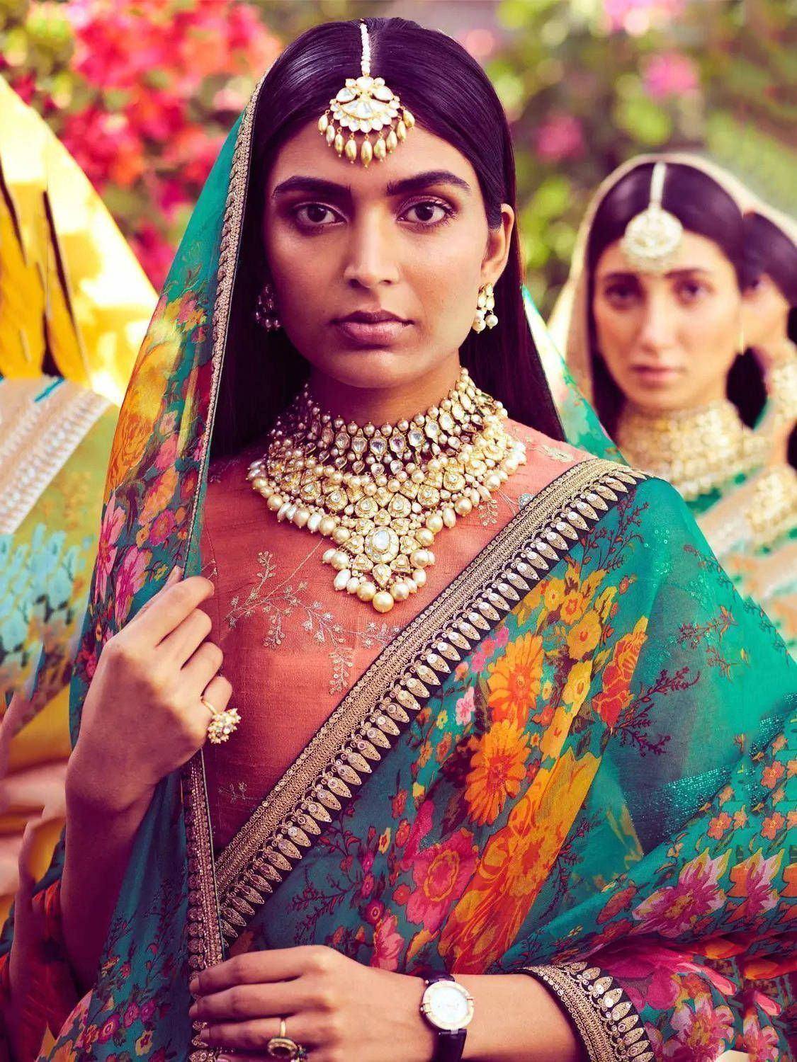 Woman in vibrant floral saree with gold jewelry, traditional Indian ethnic wear