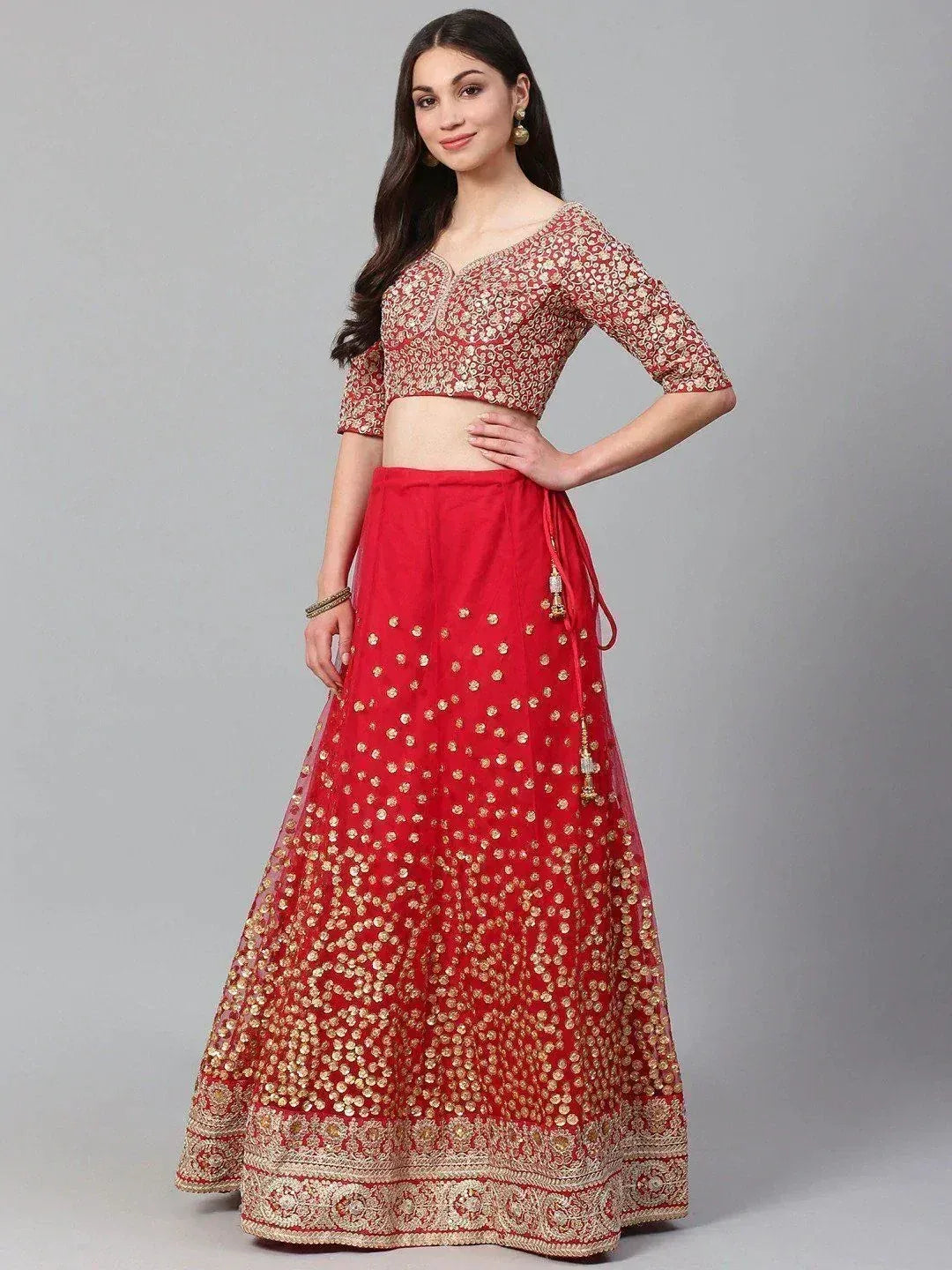 Red and gold embroidered lehenga choli with floral motifs and tassel details, perfect for Indian ethnic occasions.