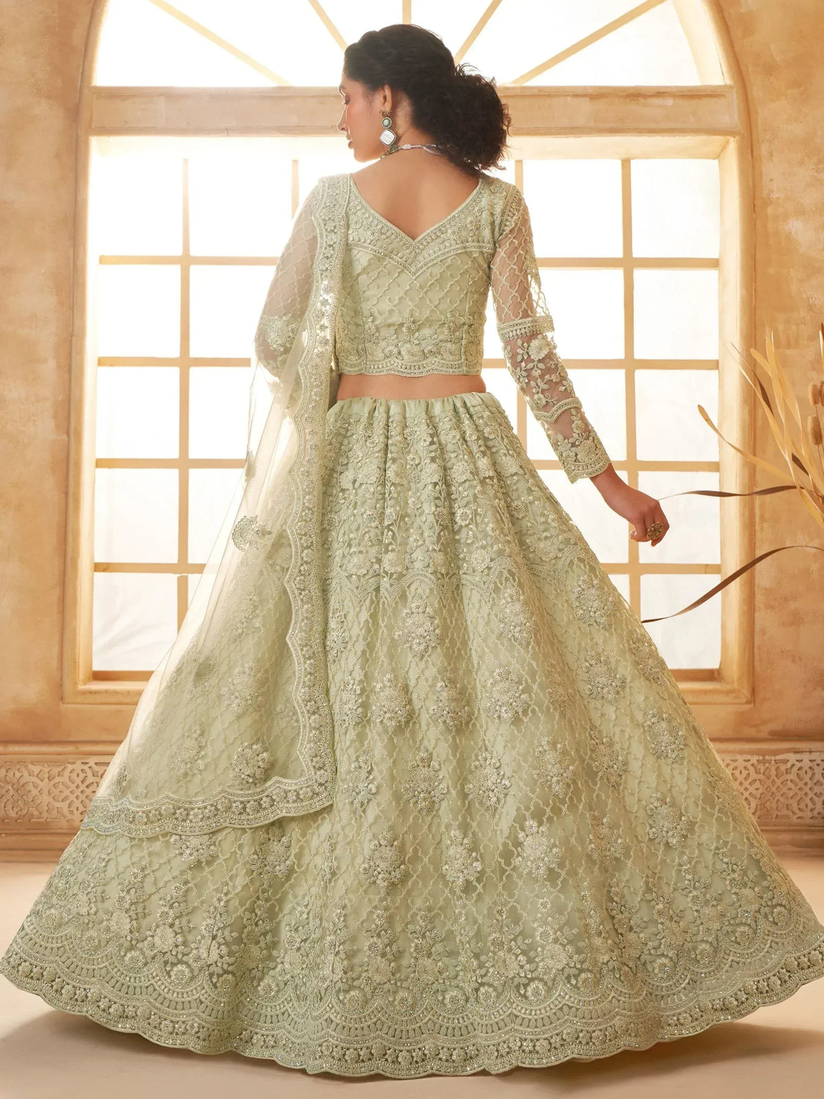 Elegant mint green designer lehenga choli with intricate embroidery and sheer sleeves, perfect for Indian weddings.