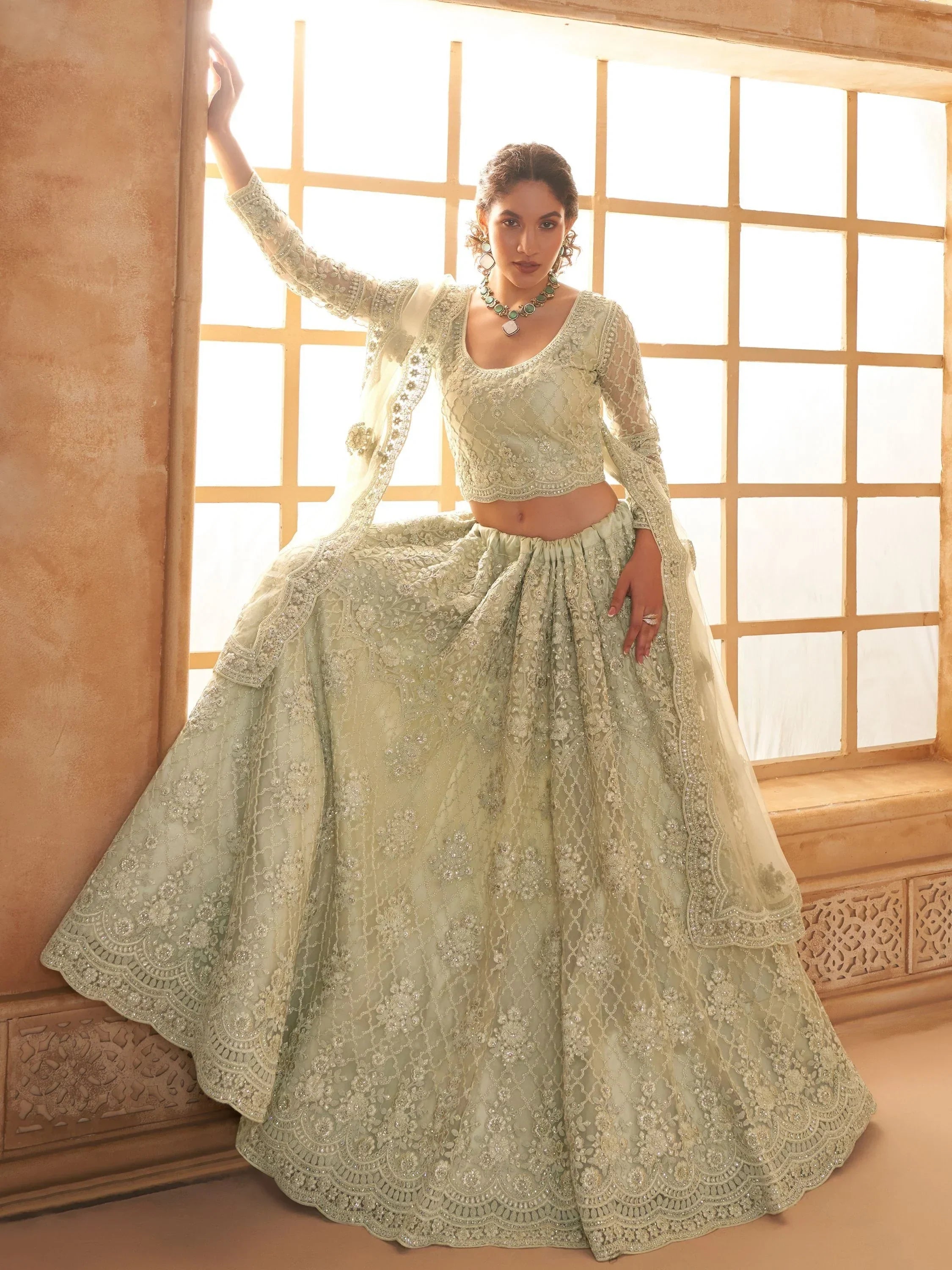 Elegant mint green designer lehenga choli with intricate embroidery and sheer dupatta, perfect for Indian weddings.