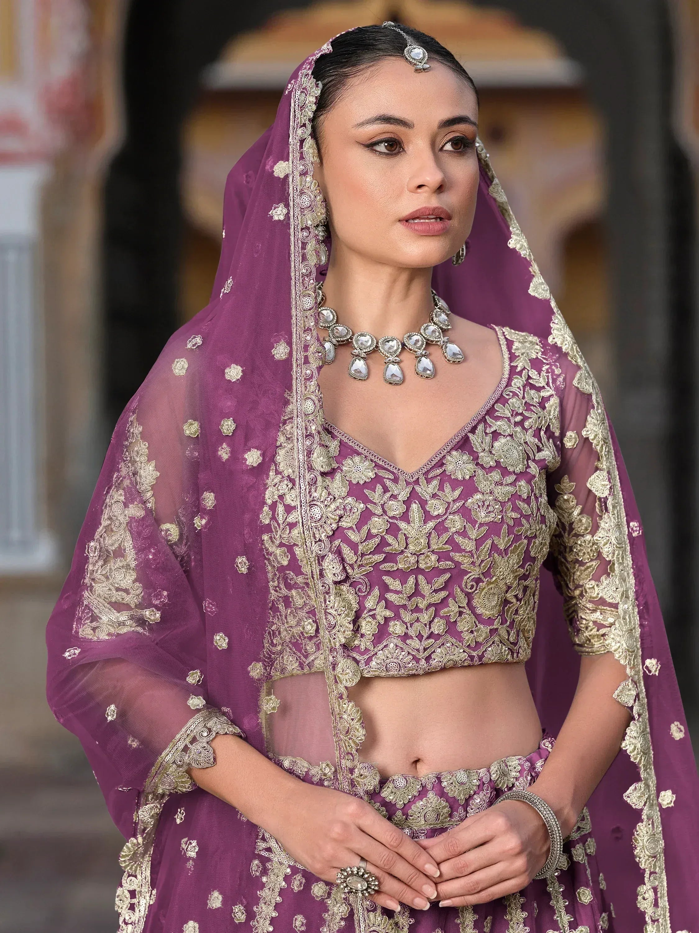 Purple embroidered lehenga choli with gold floral work, dupatta, and traditional jewelry for Indian ethnic wear