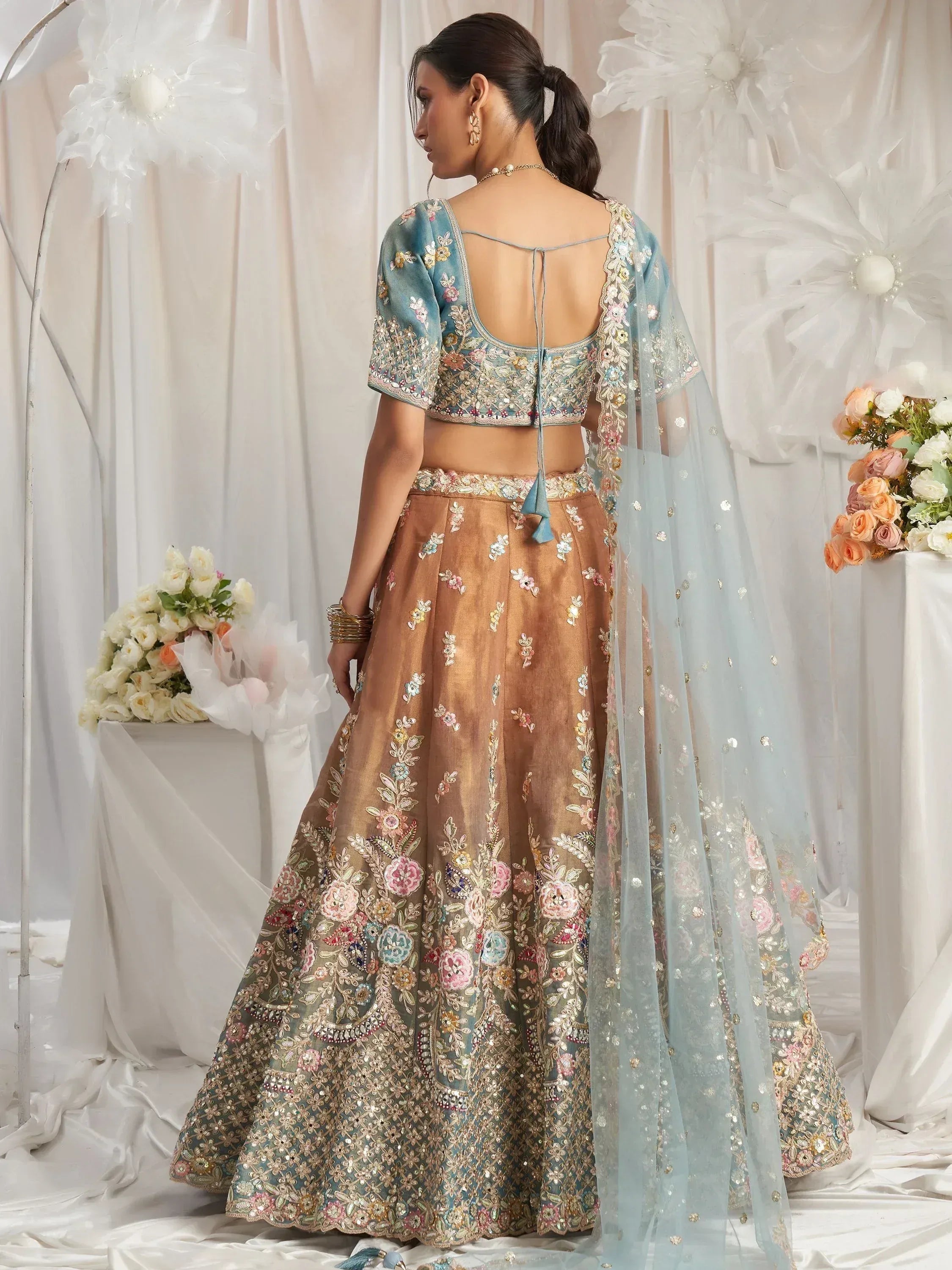 Elegant floral embroidered lehenga choli with open back blouse and sheer dupatta, perfect for Indian weddings.