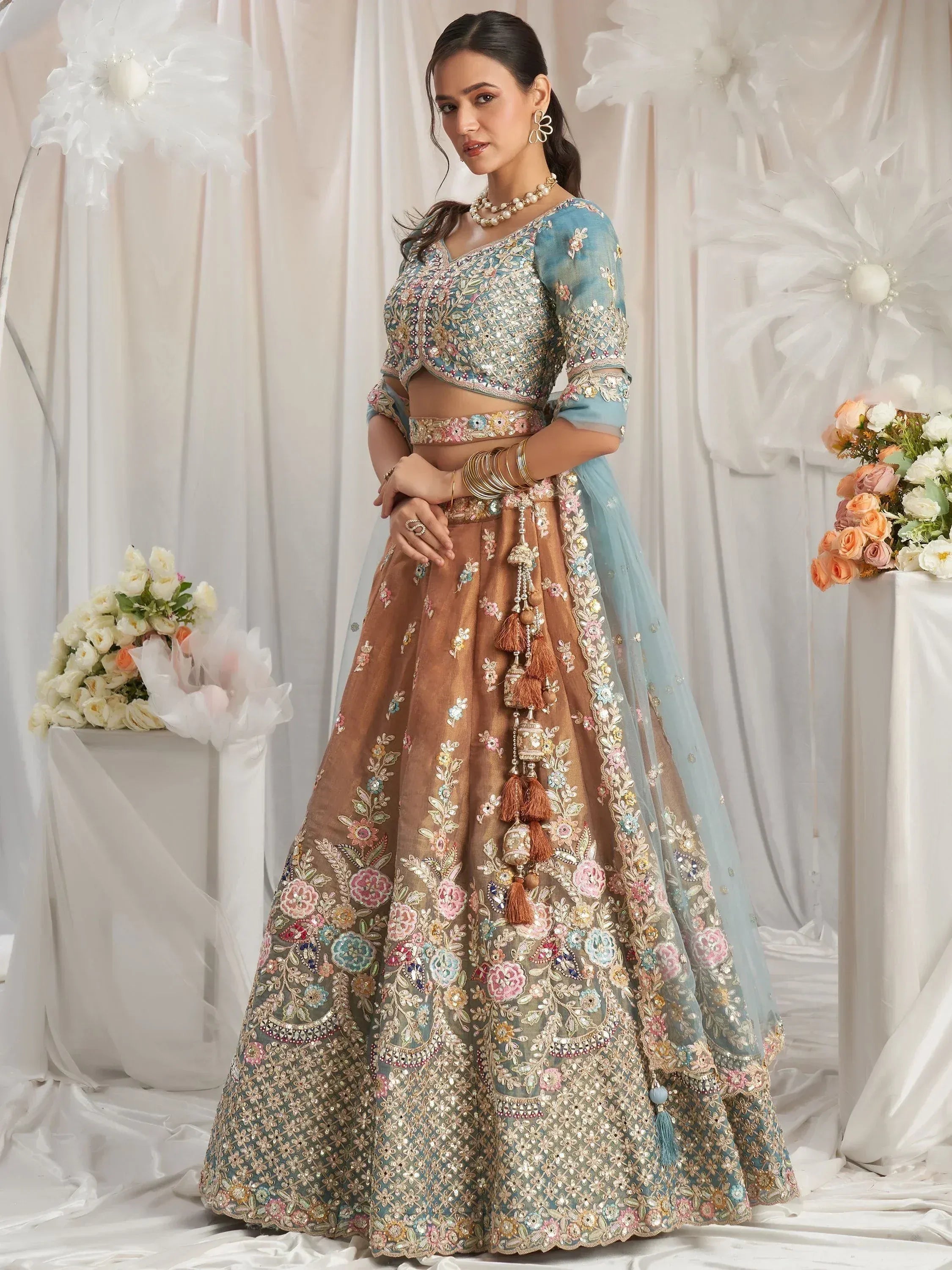 Elegant floral embroidered lehenga choli with pastel blue blouse and brown skirt, perfect for Indian weddings.