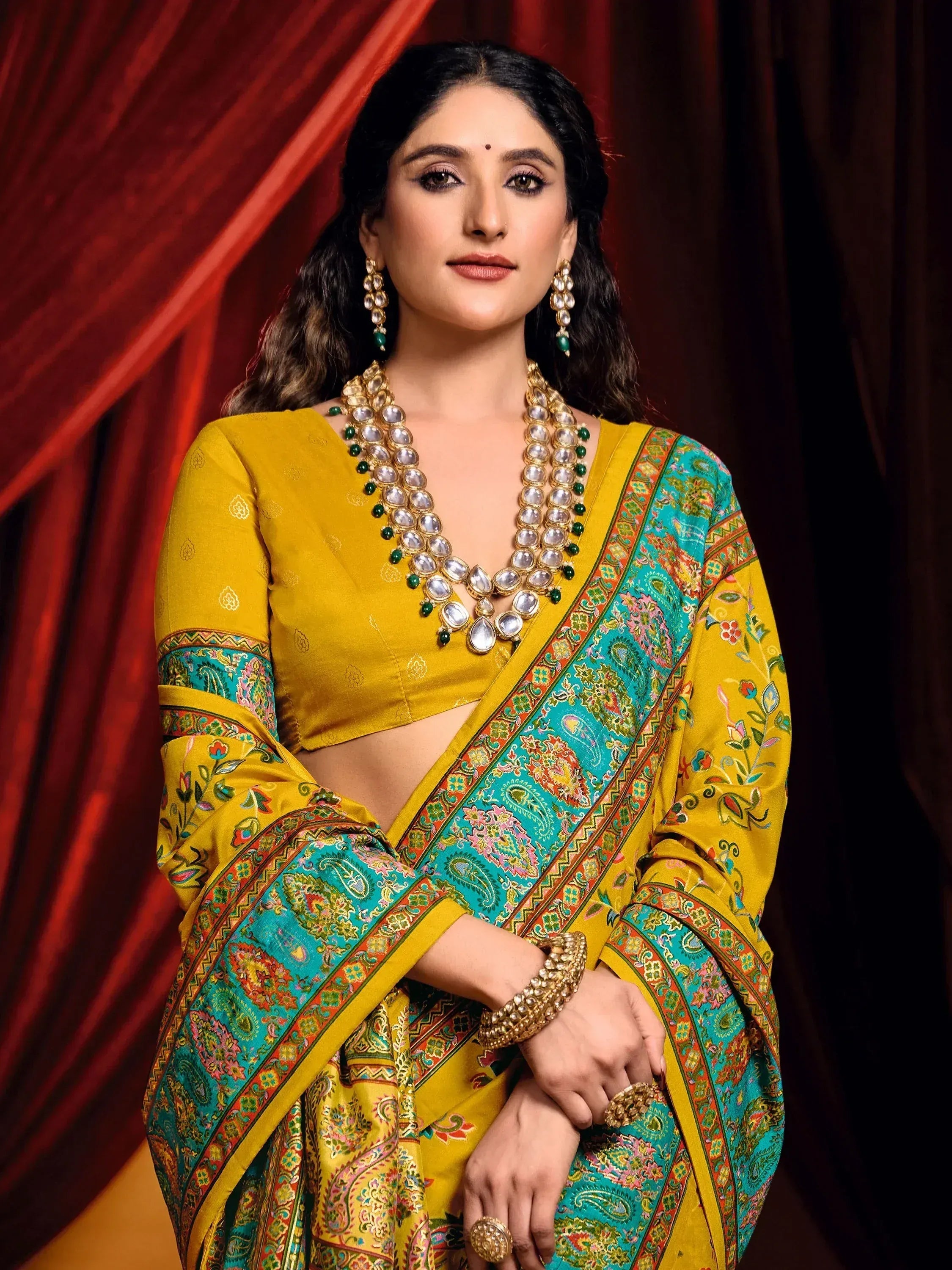Yellow and turquoise designer saree with intricate paisley print, paired with traditional jewelry for ethnic wear
