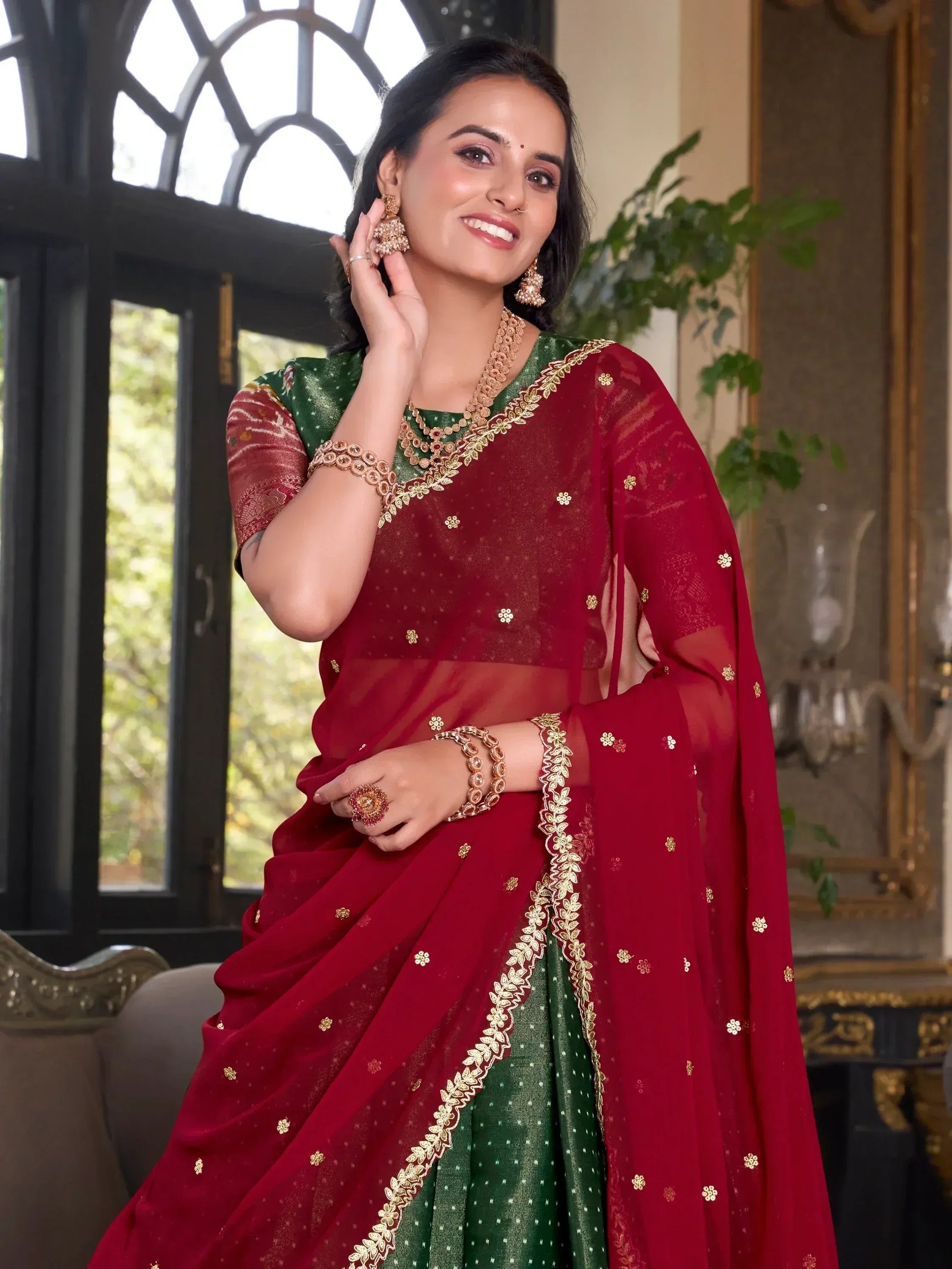 Woman in maroon and green embroidered saree with gold jewelry, elegant ethnic wear for festive occasions