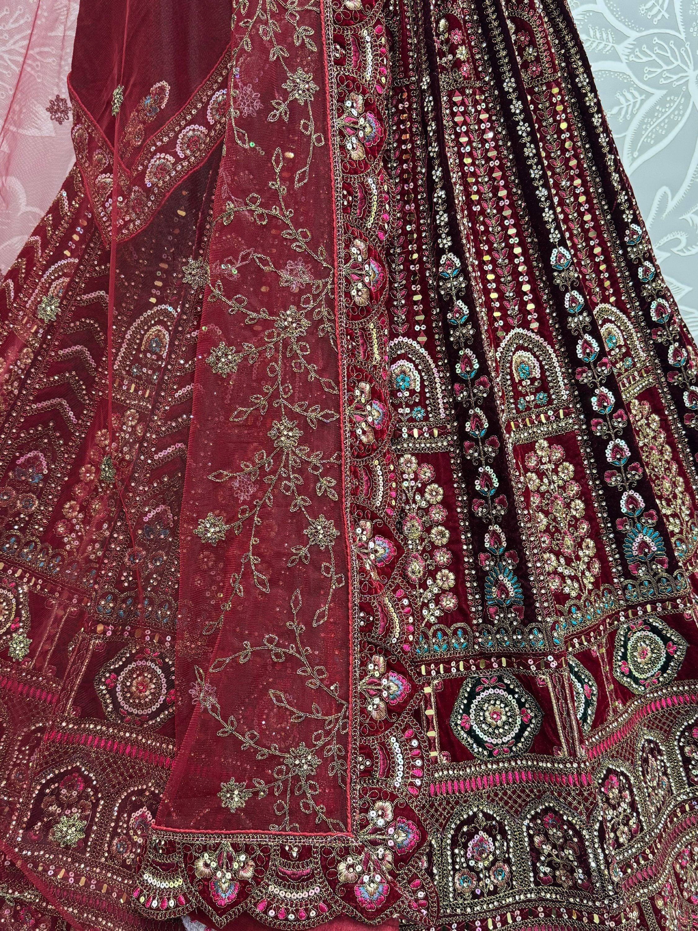 Rich maroon velvet lehenga with intricate gold embroidery and colorful sequin work, perfect for Indian weddings.