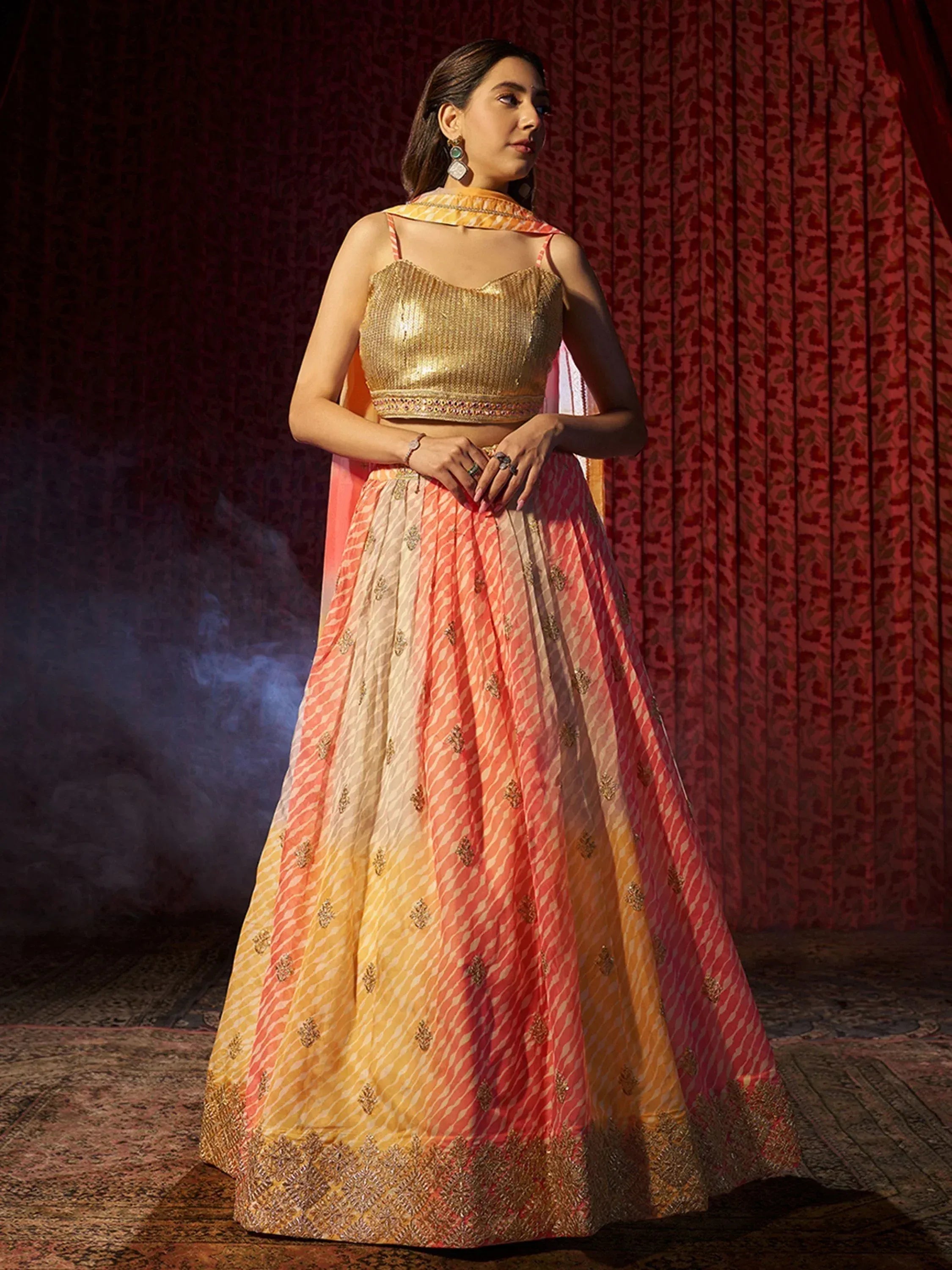 Woman in gold sequin lehenga choli with ombre pink and yellow skirt, ethnic Indian wear