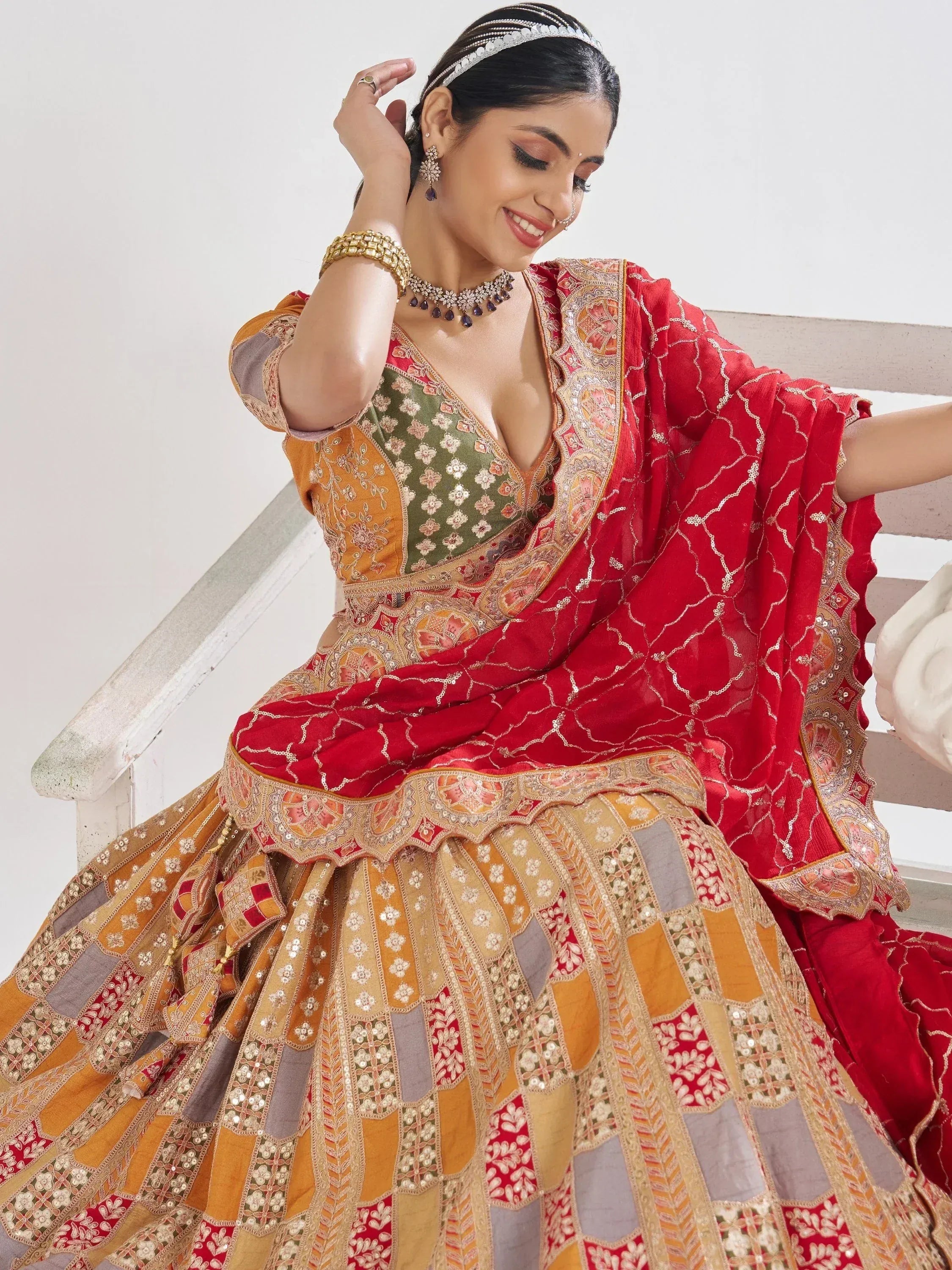 Woman in vibrant red and gold embroidered lehenga choli with floral patterns, perfect for Indian weddings or festivals.