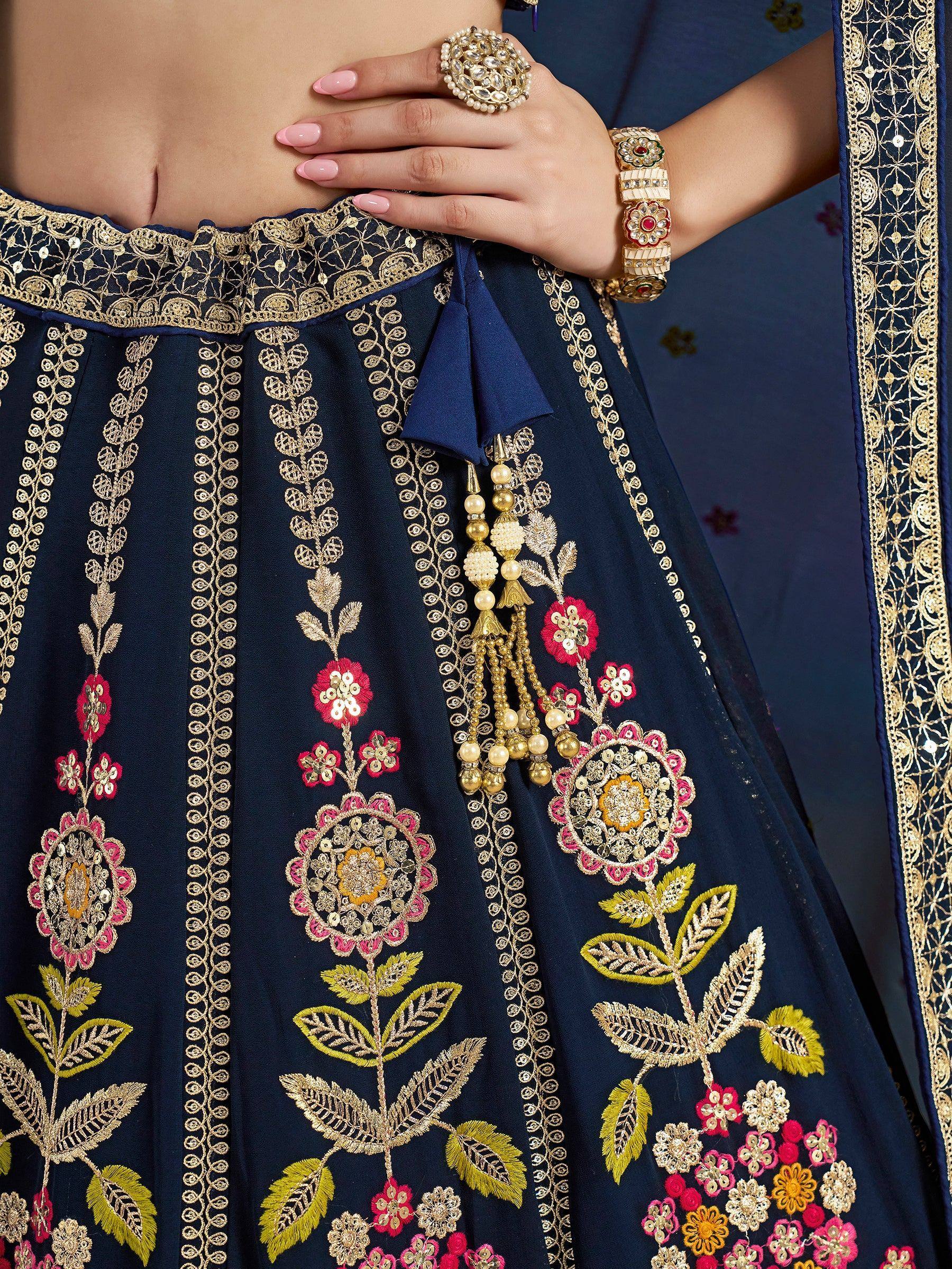 Navy blue lehenga with gold and pink floral embroidery, tassels, and traditional Indian jewelry