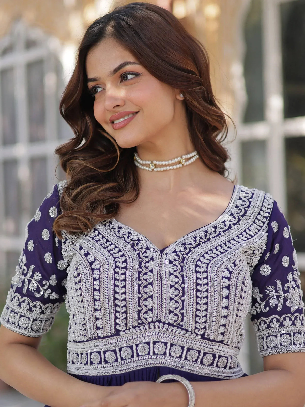 Woman in purple ethnic gown with silver embroidery, pearl choker, and bangles