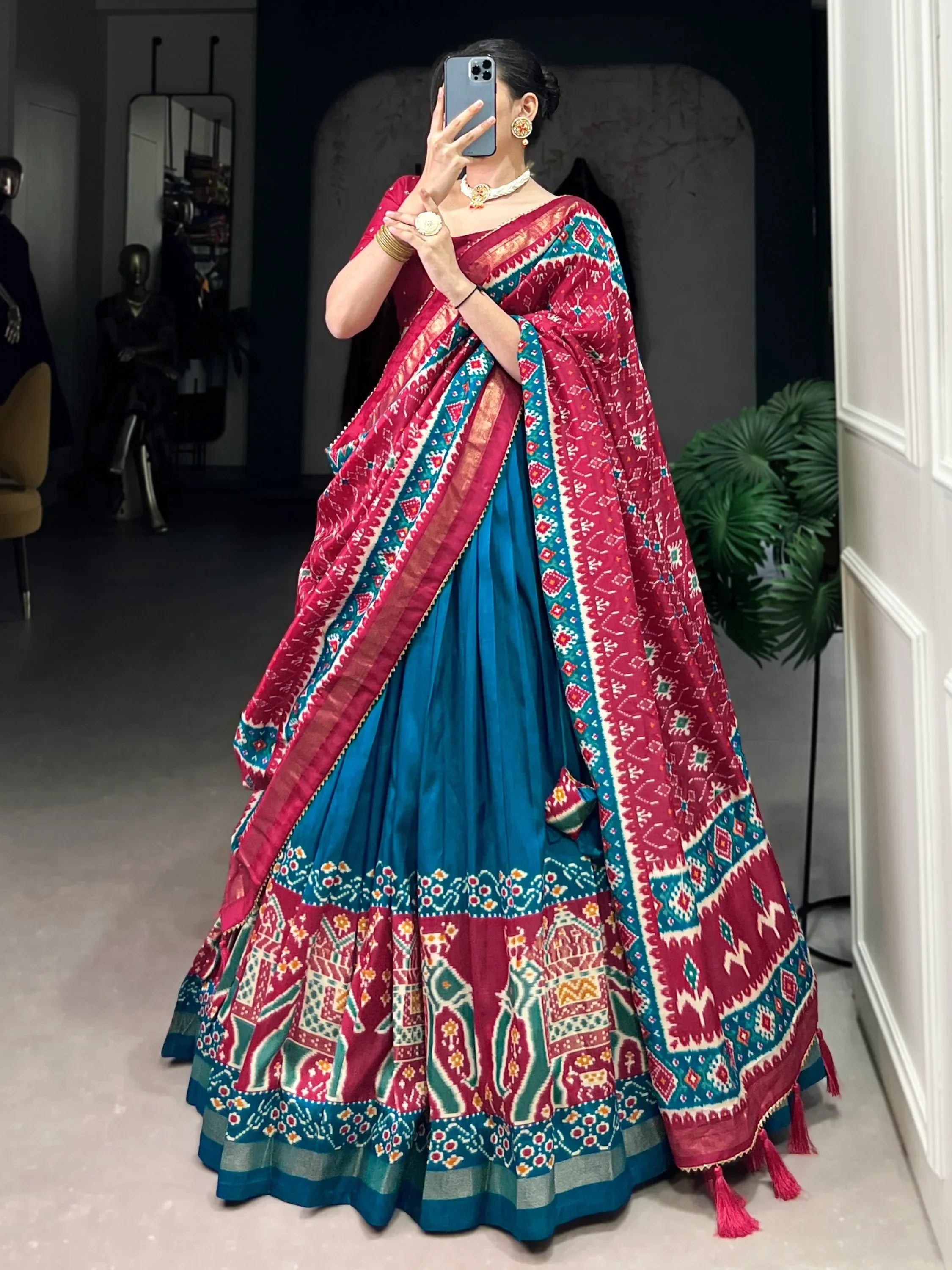 Woman in vibrant red and blue printed lehenga choli with ethnic patterns, perfect for Indian weddings or festivals.