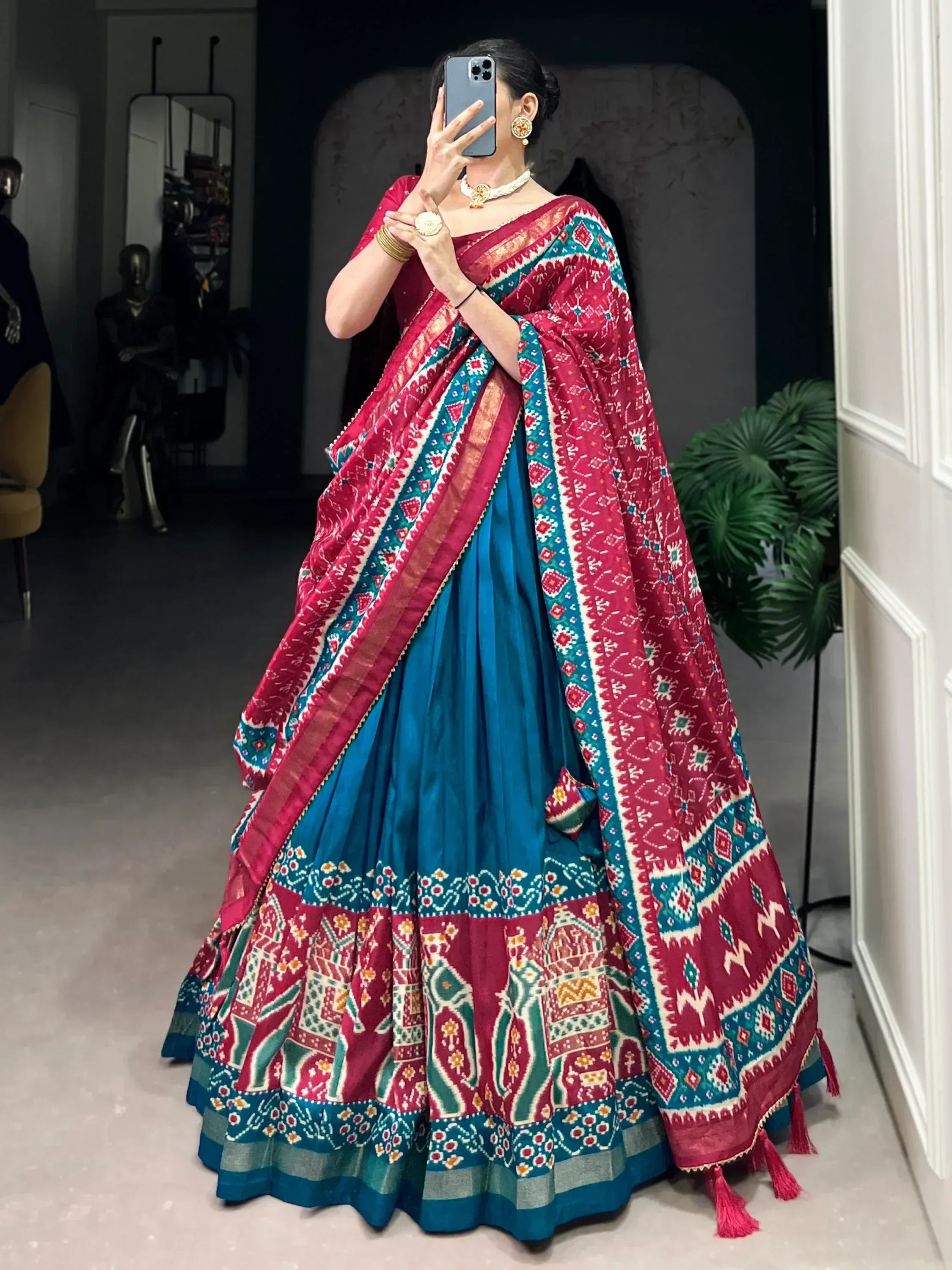 Woman in vibrant red and blue printed lehenga choli with ethnic patterns, perfect for Indian weddings or festivals.
