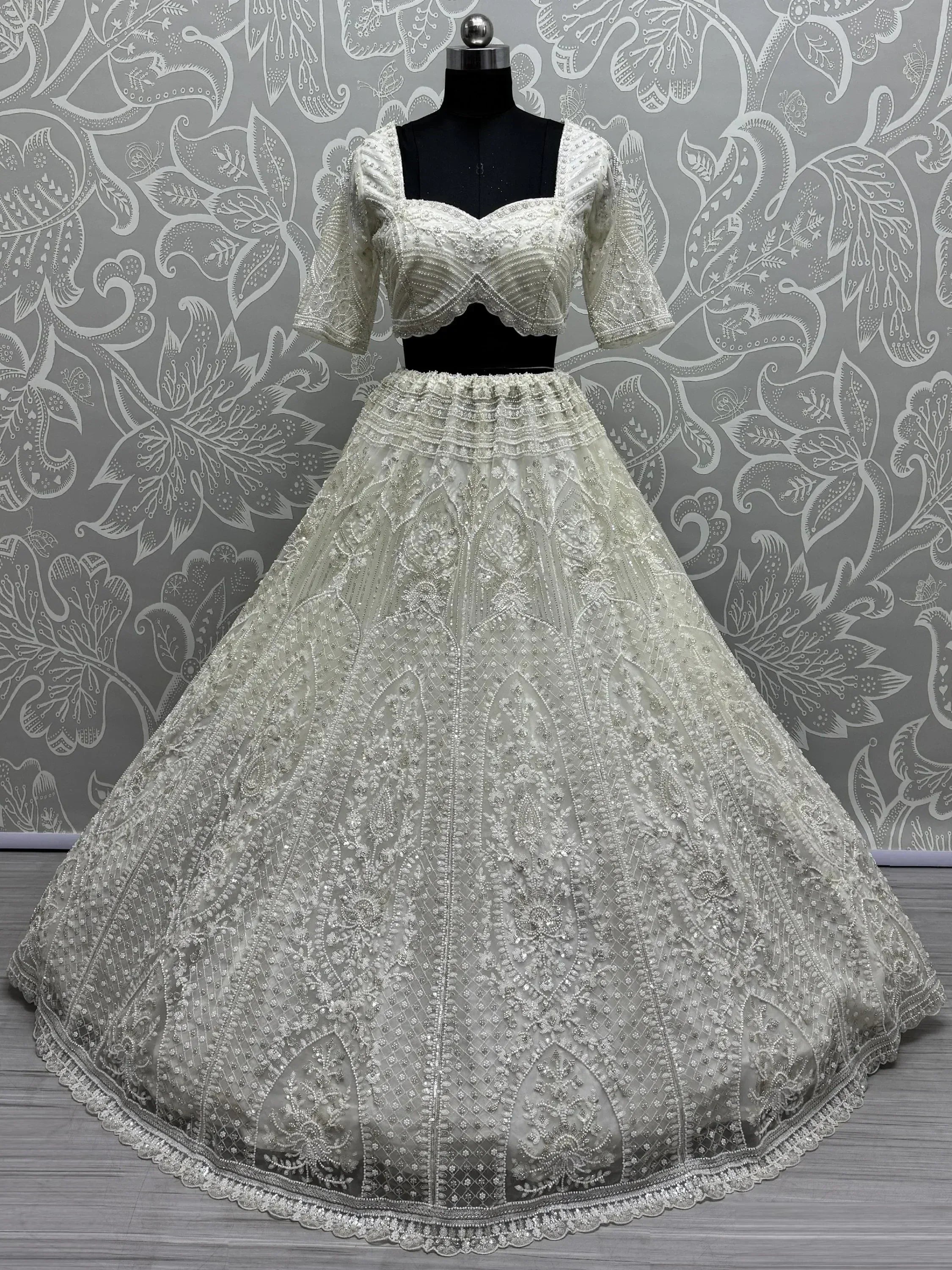 Elegant white embroidered lehenga choli with detailed beadwork, perfect for Indian weddings and festive occasions.
