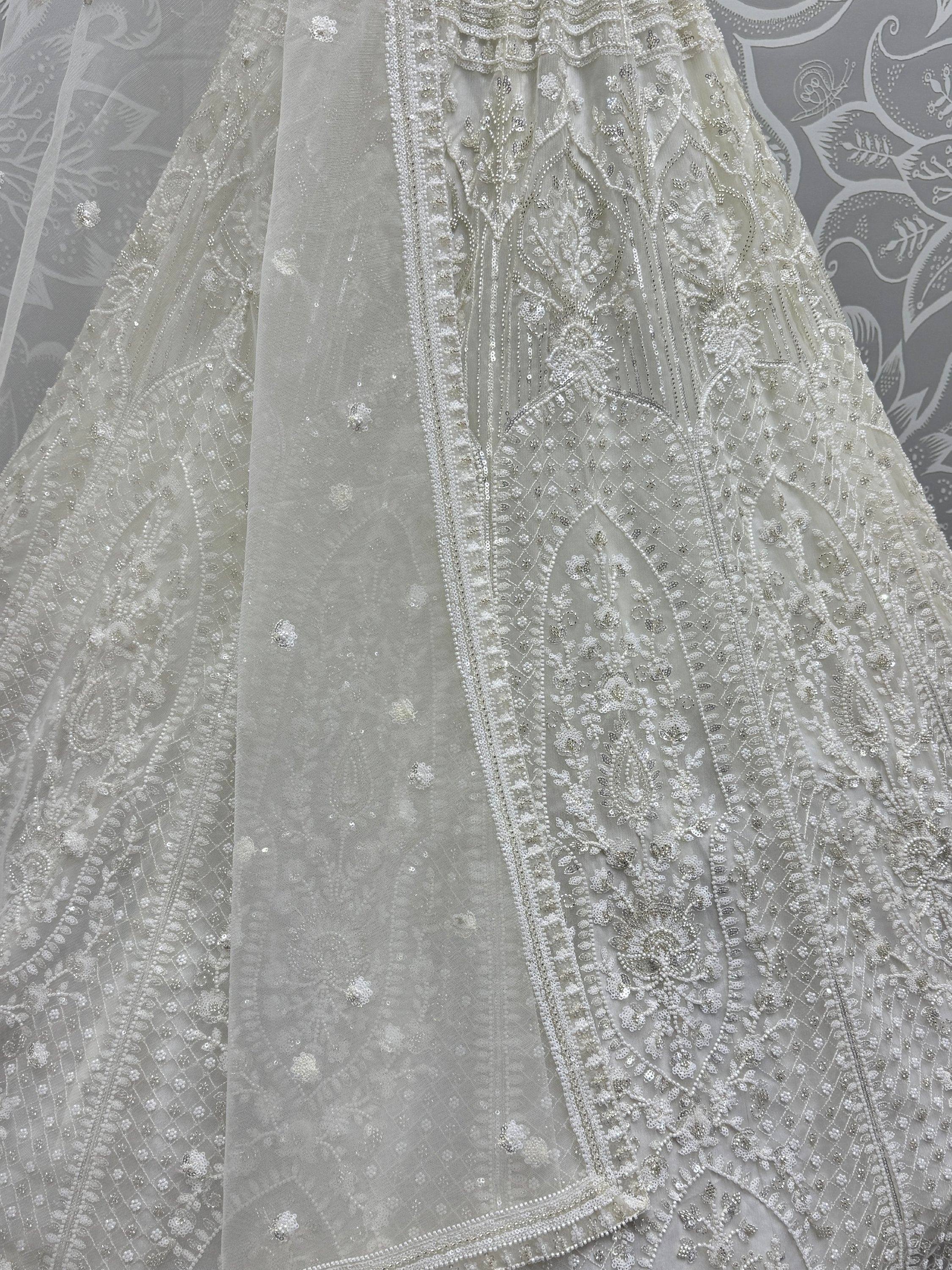 Elegant white ethnic gown with intricate beadwork and floral embroidery, perfect for weddings or festive occasions.