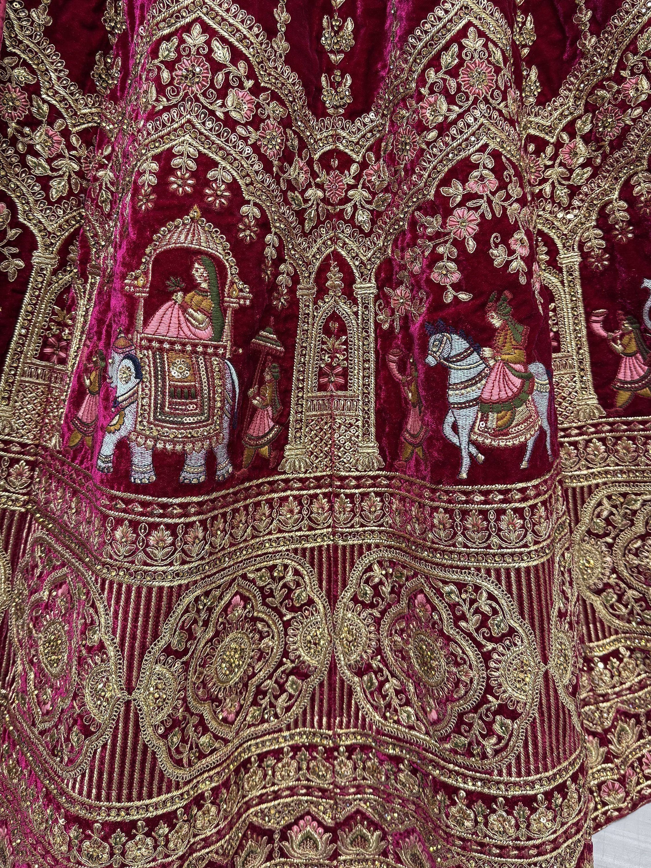 Richly embroidered maroon ethnic wear with gold detailing, featuring royal motifs and intricate designs.