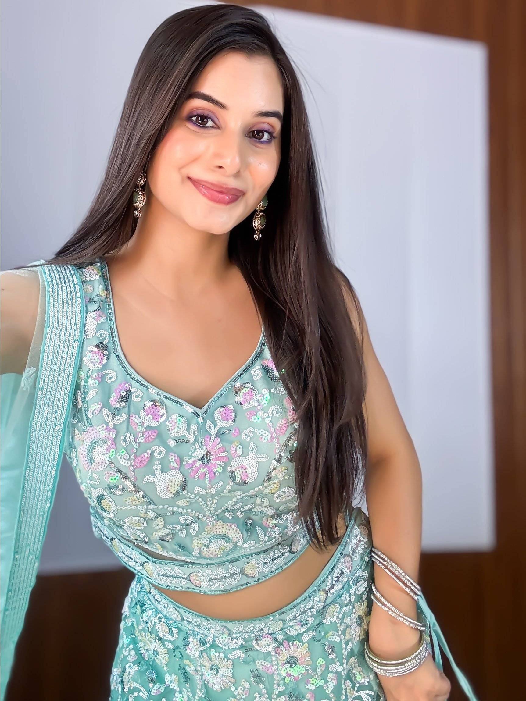 Woman in mint green sequin lehenga choli with floral embroidery, perfect for Indian ethnic wear occasions.