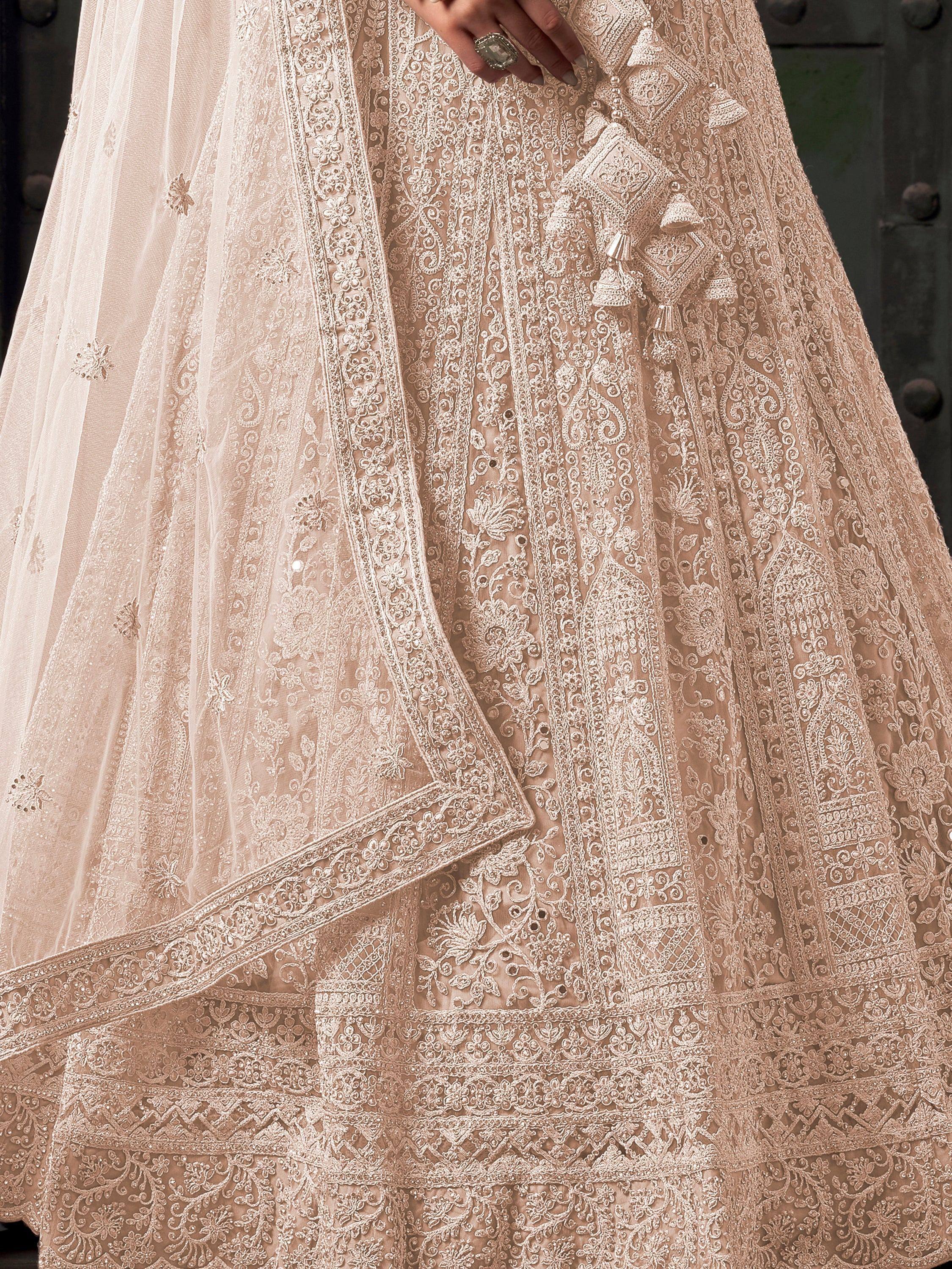 Elegant beige designer lehenga choli with intricate floral embroidery and tassels, perfect for Indian weddings.